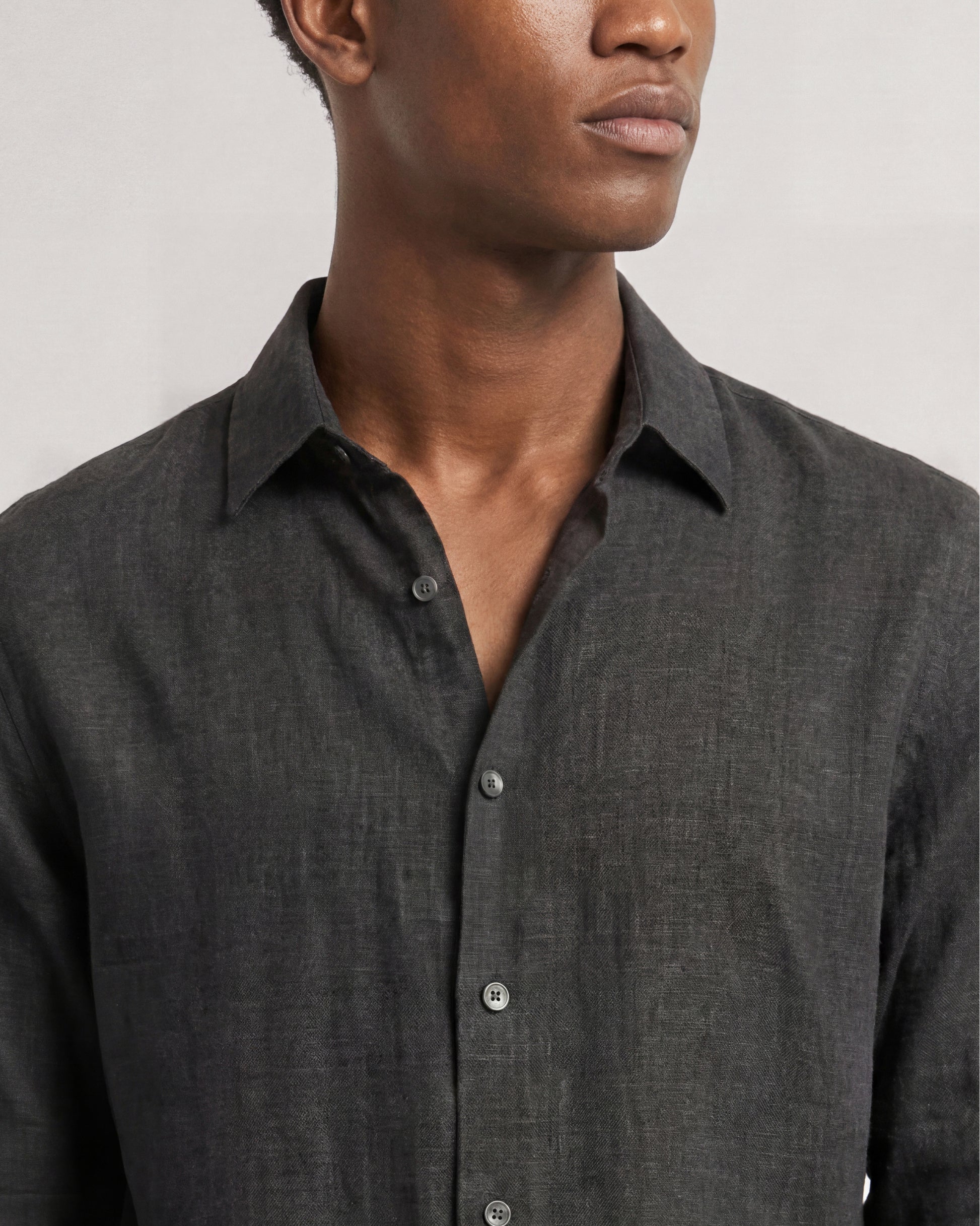 Man wearing a dark gray button-up shirt against a plain background