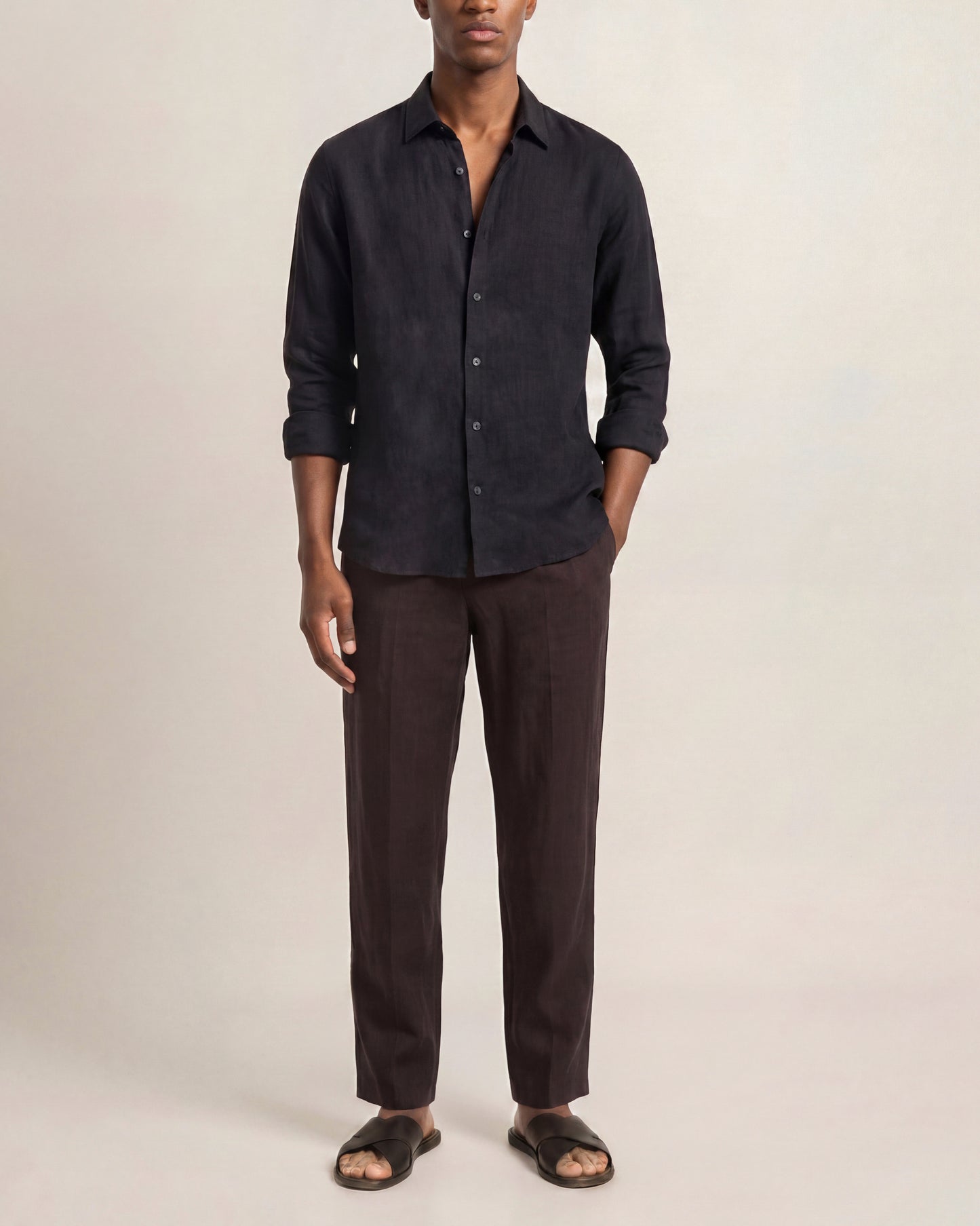 Man wearing a dark shirt and brown pants on a plain background