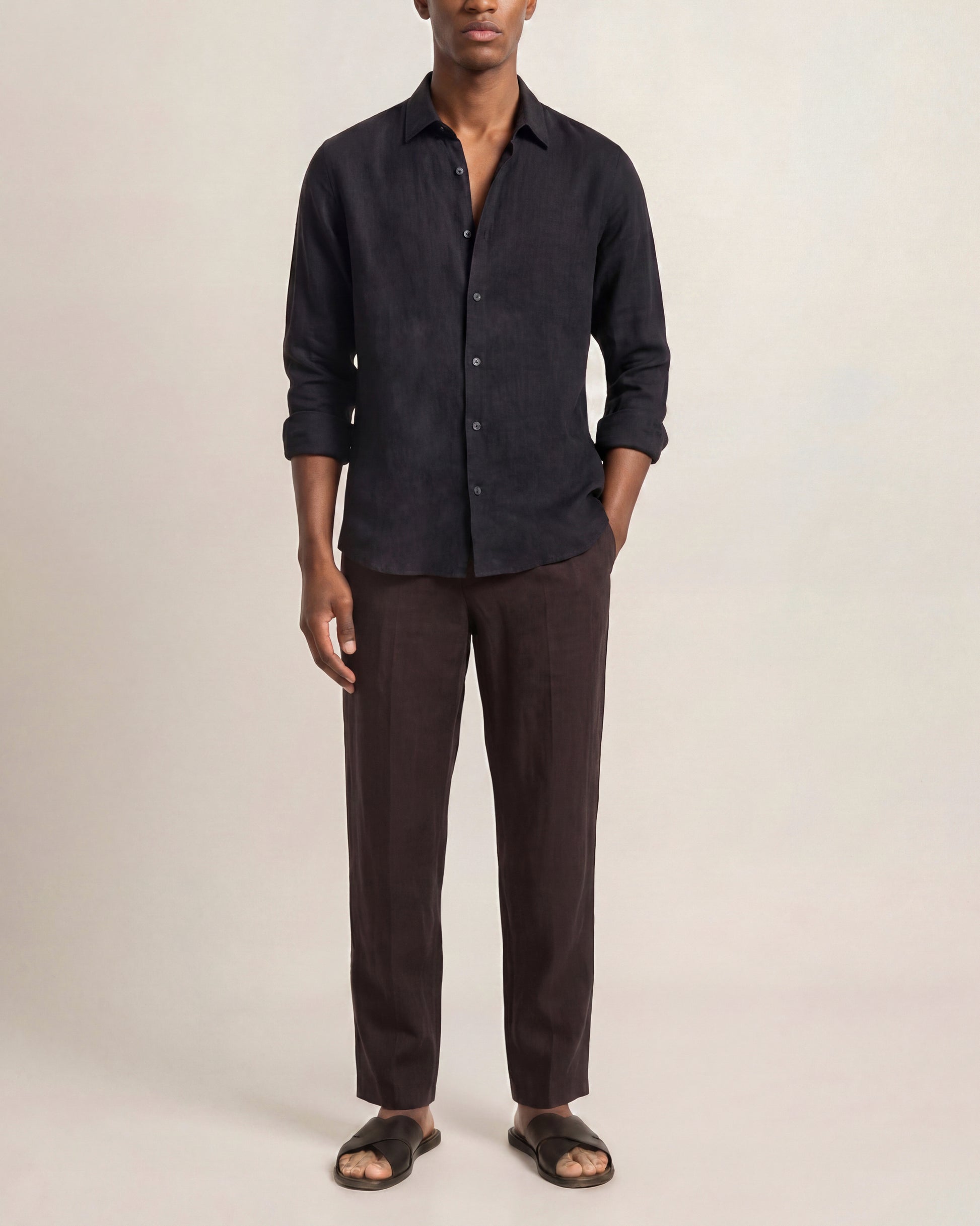 Man wearing a dark shirt and brown pants on a plain background
