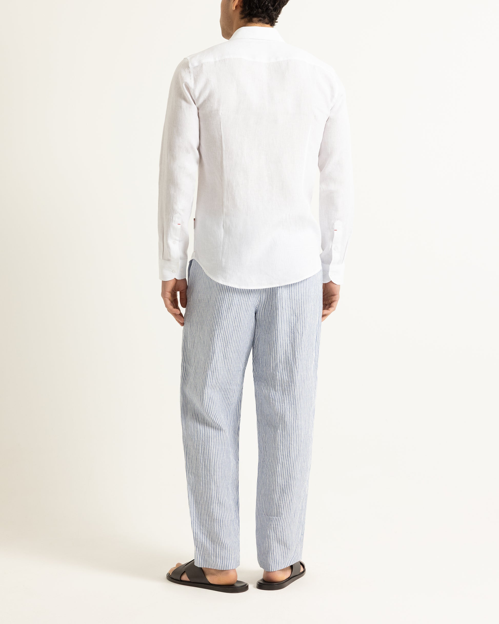 Person wearing a white shirt and light gray pants on a white background