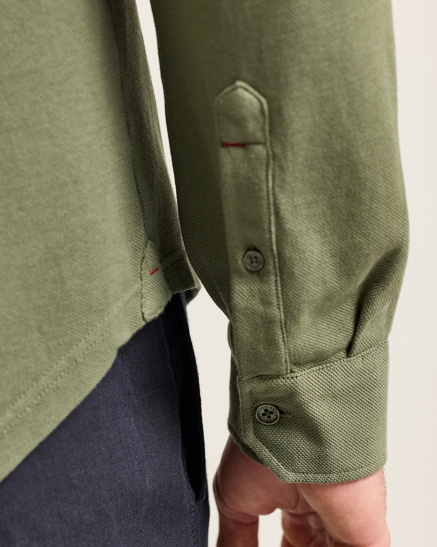 Close-up of a green shirt with button details on a plain background