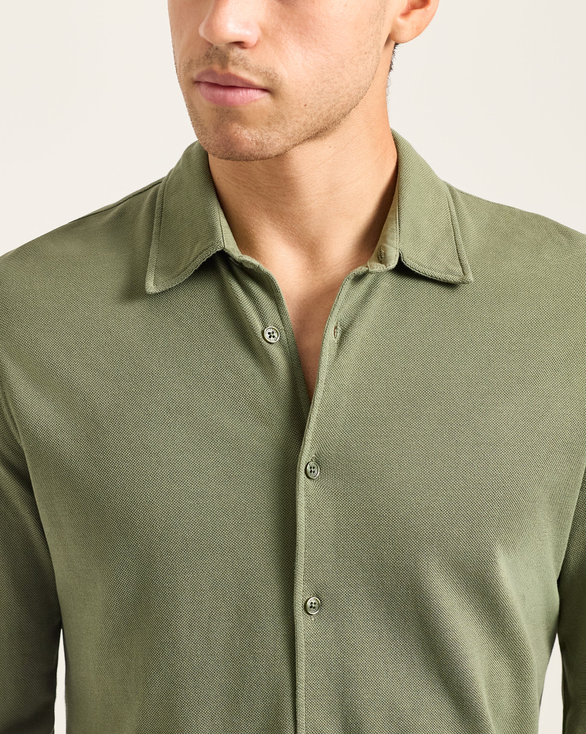 Man wearing a green long-sleeve shirt against a plain background
