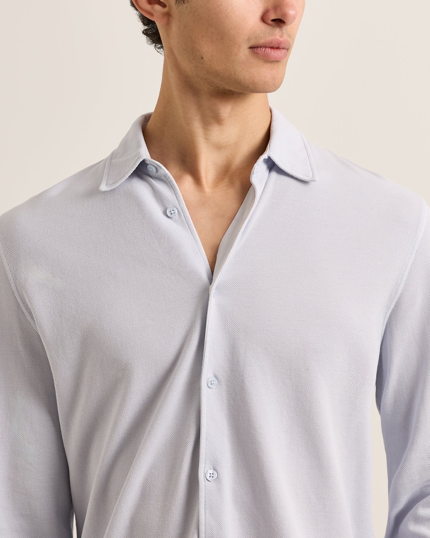 Man wearing a light gray shirt against a neutral background