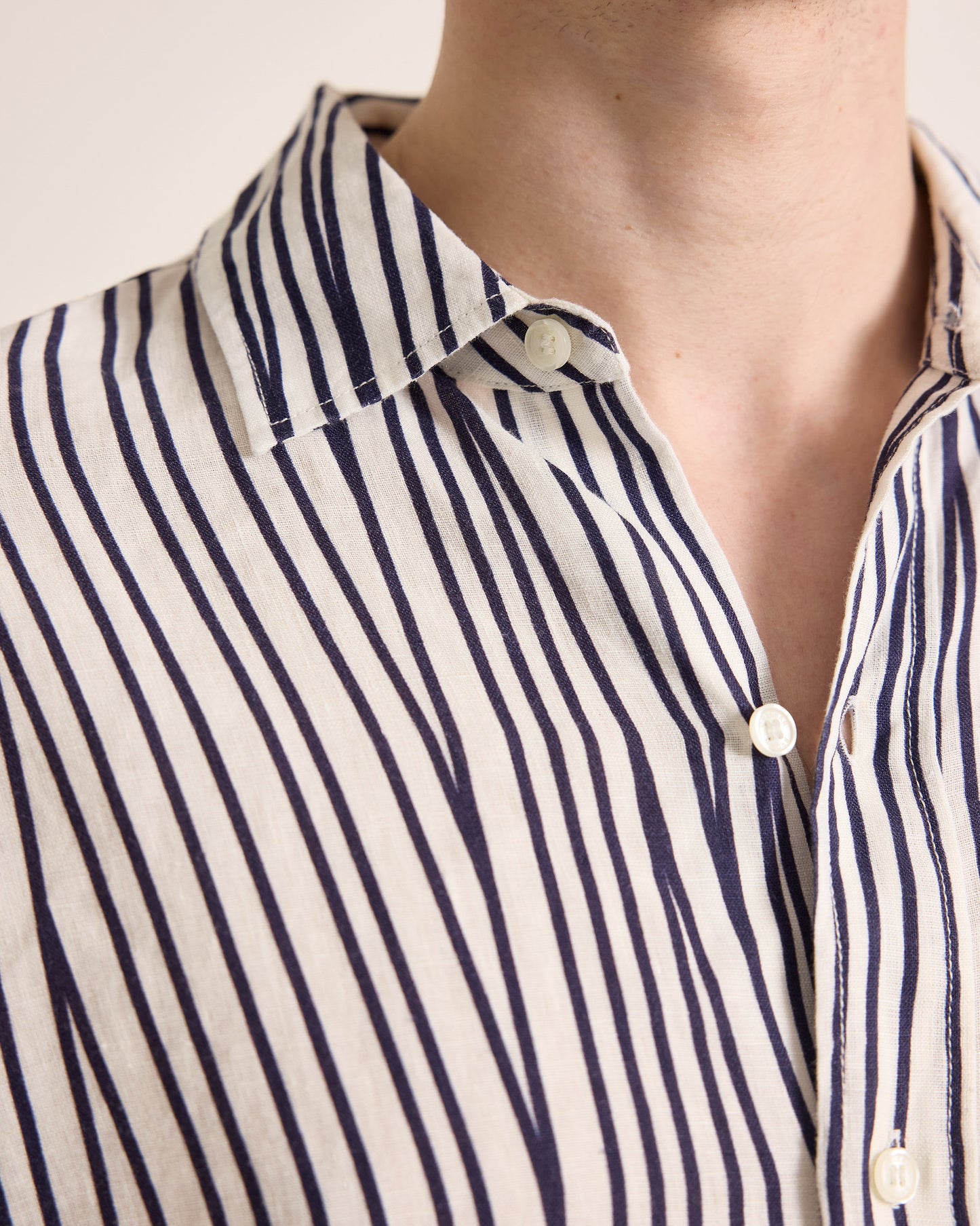 Close-up of a person wearing a navy and white striped shirt with a neutral background