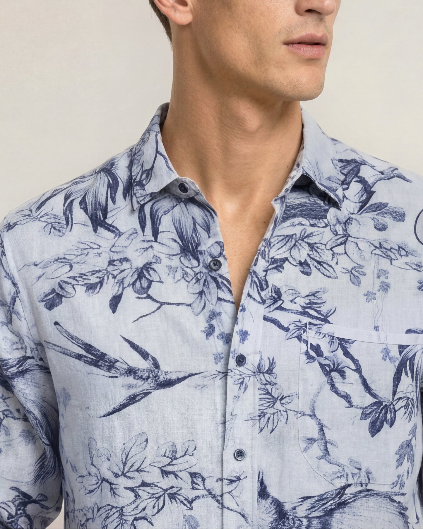 Closeup of man wearing printed blue shirt on a plain background