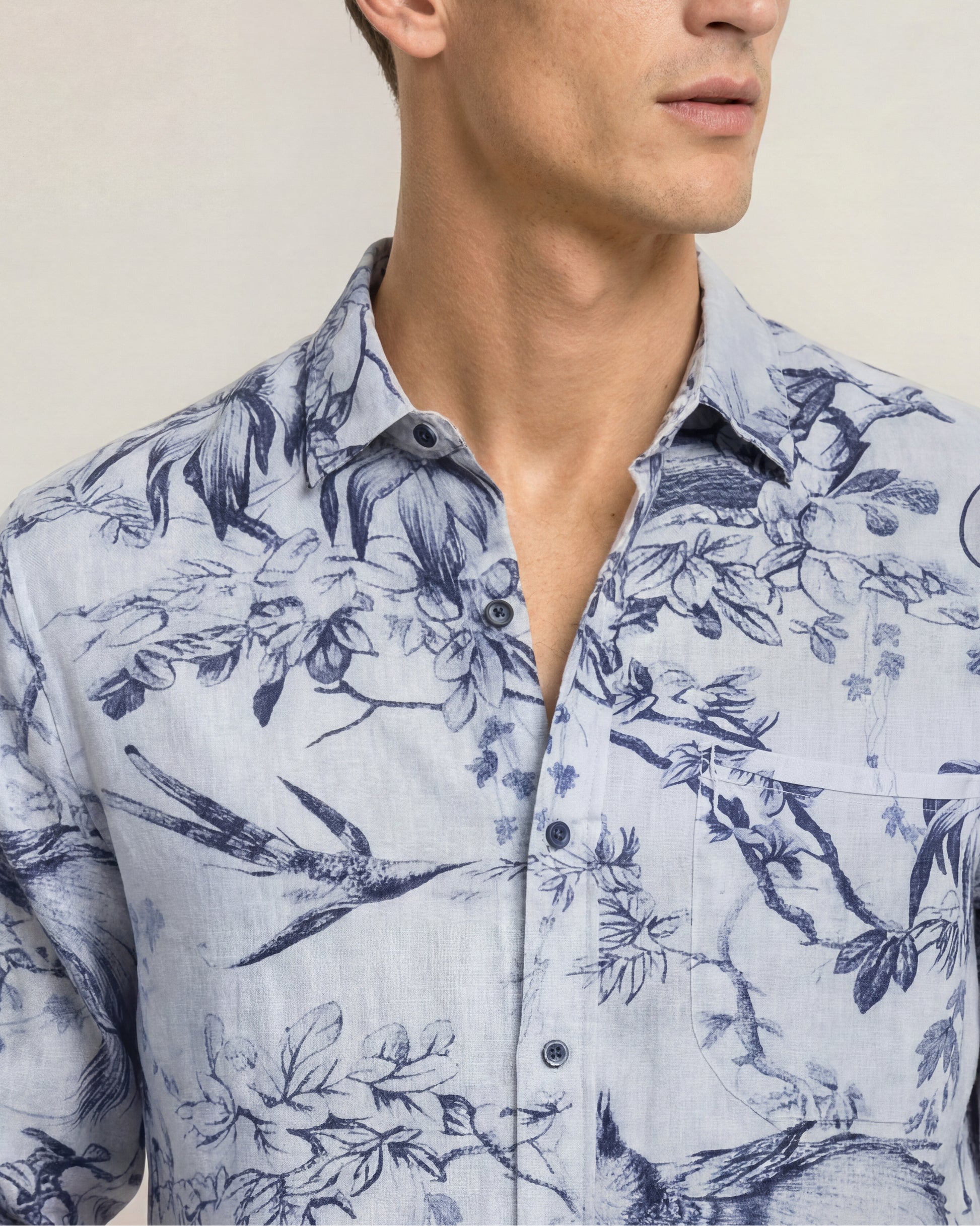 Closeup of man wearing printed blue shirt on a plain background