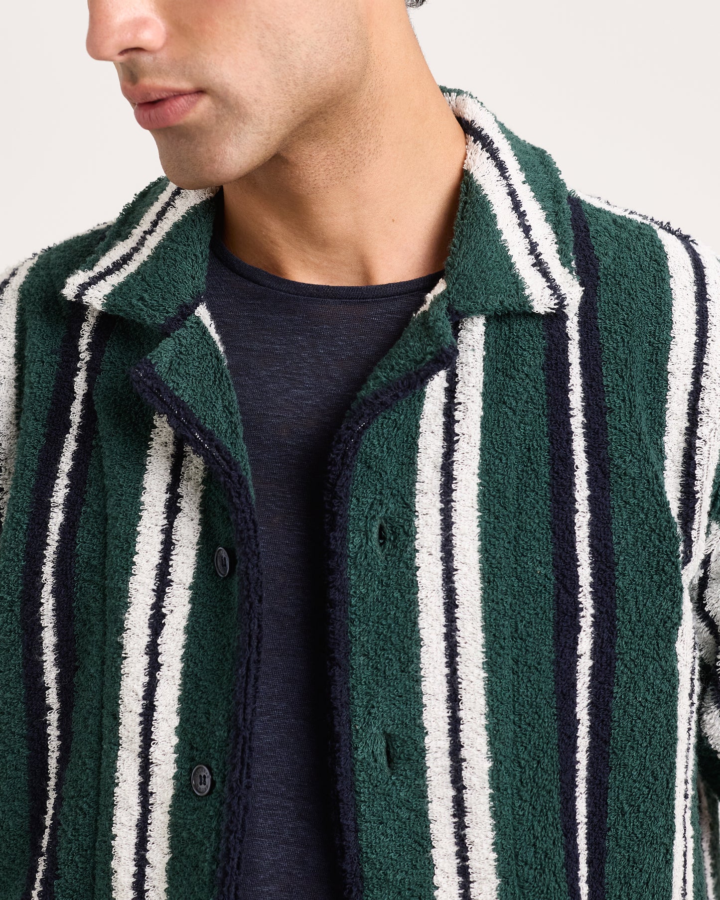 Close-up of model wearing green and white striped towelling shirt on a white background