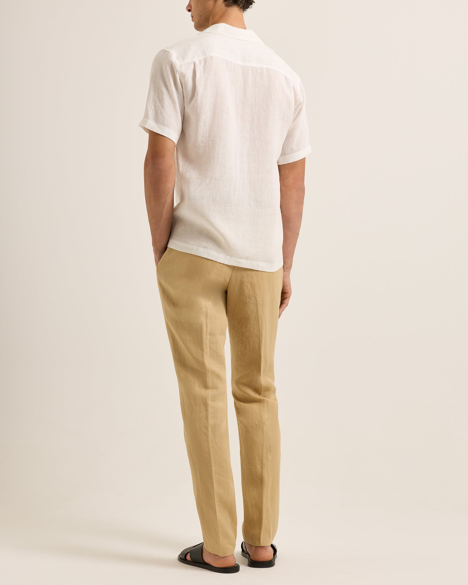 Person wearing a white shirt and beige pants on a plain background
