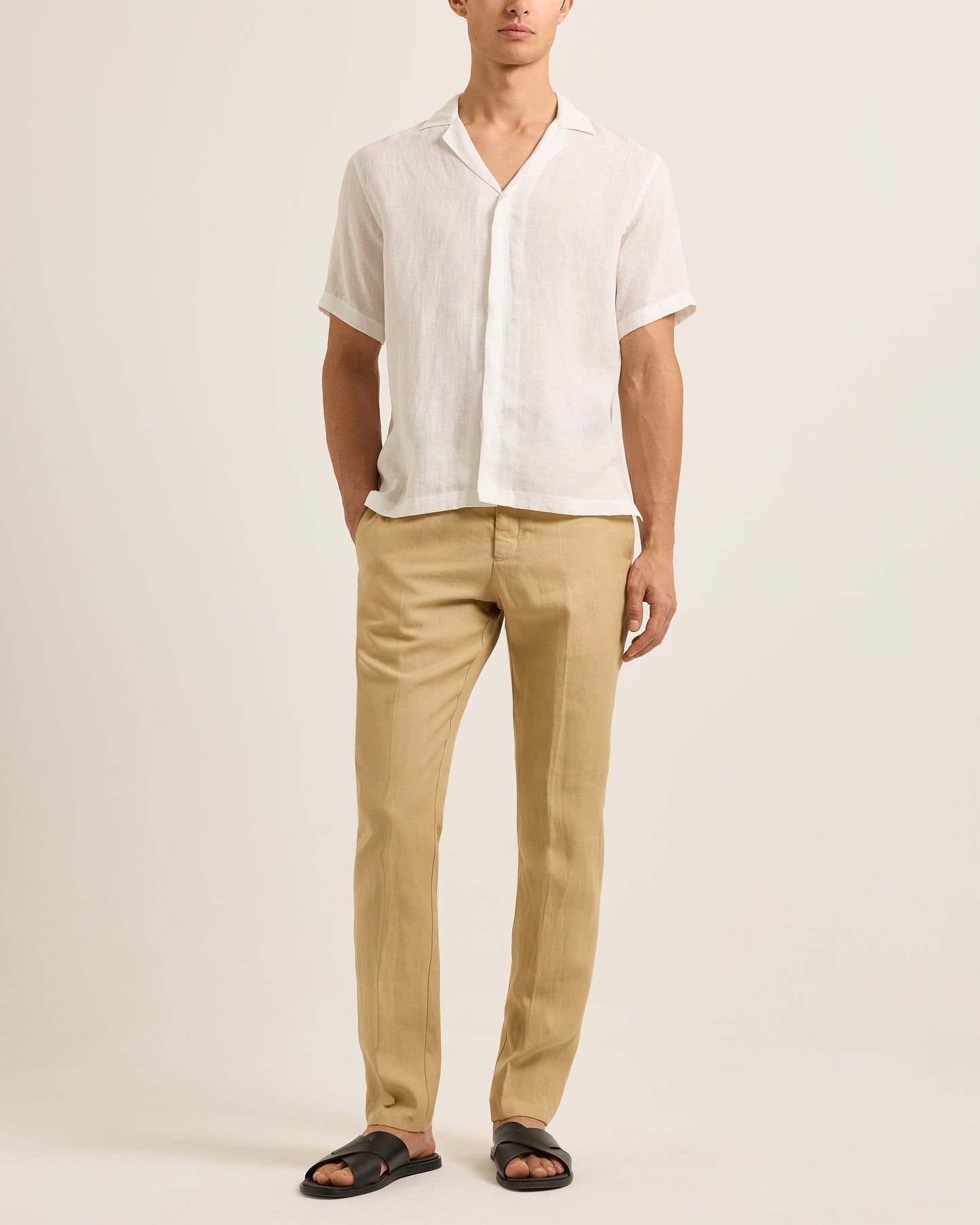 Person wearing a white shirt and beige pants on a plain background