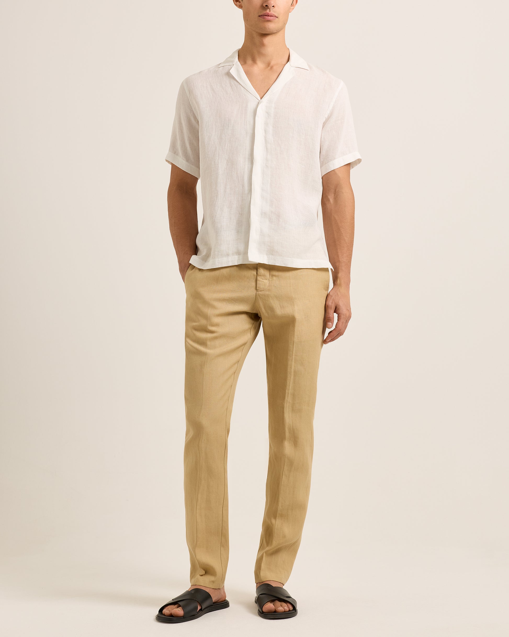 Person wearing a white shirt and beige pants on a plain background