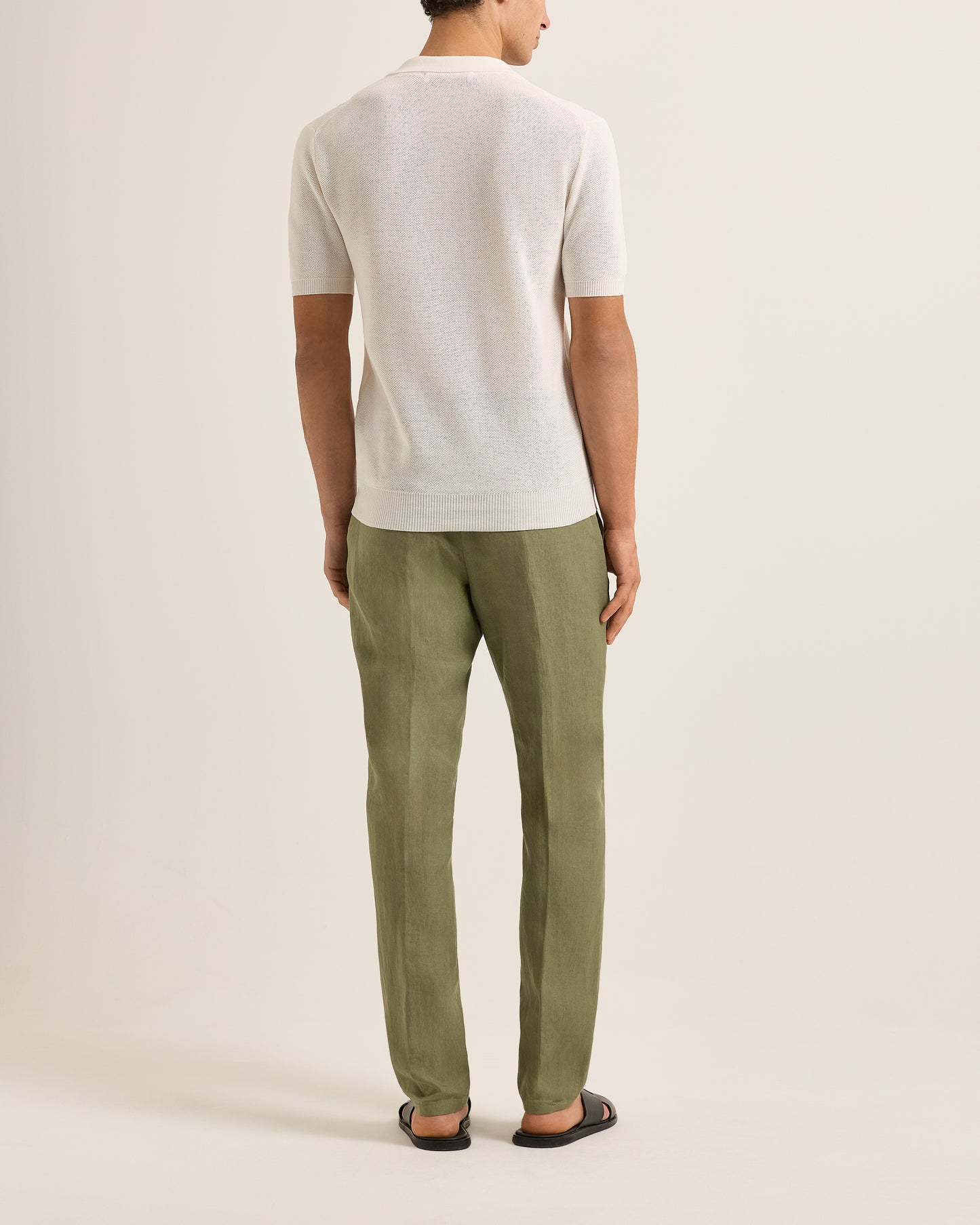 Person wearing a white shirt and green pants on a plain background