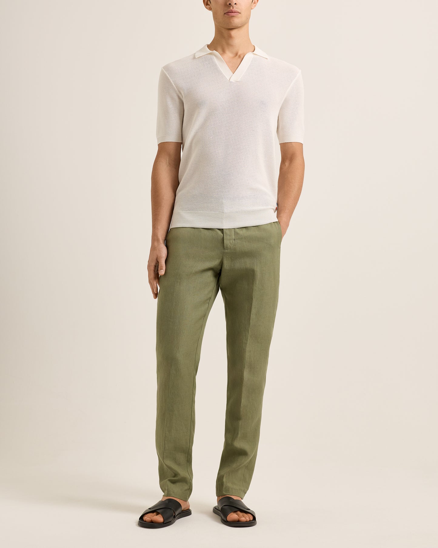 Person wearing a white shirt and green pants on a plain background