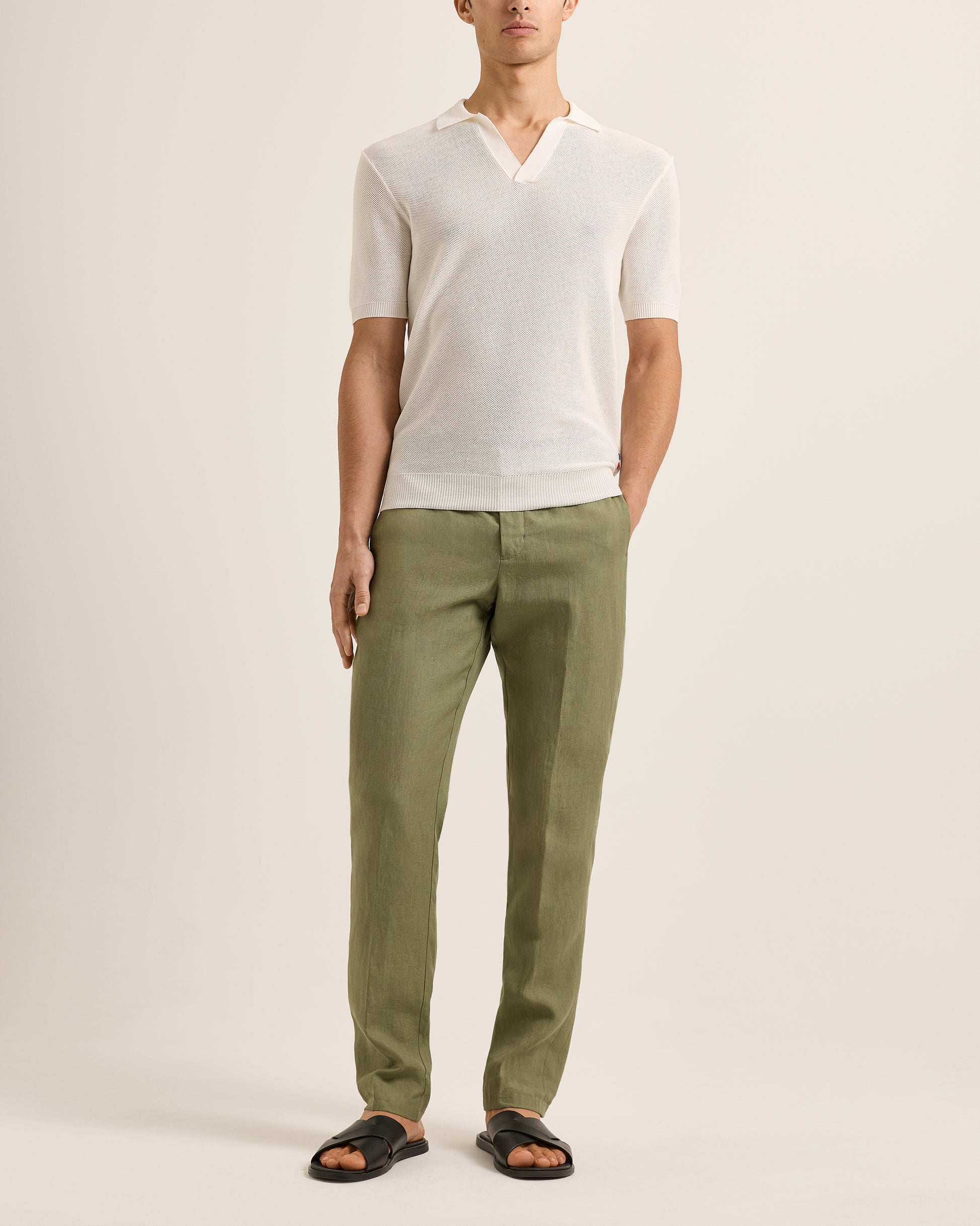 Person wearing a white shirt and green pants on a plain background
