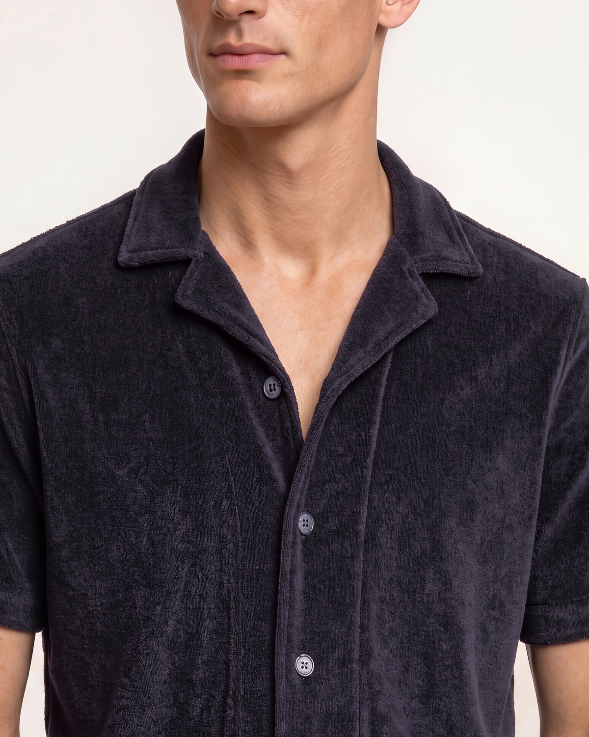 Man wearing navy towelling button up shirt with revere collar on a plain background