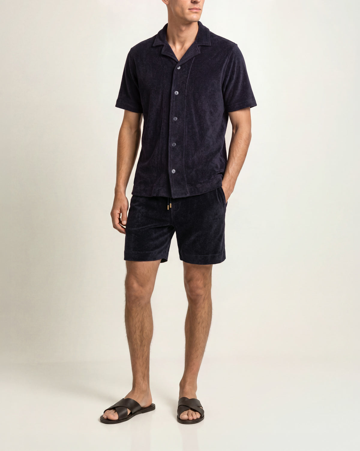 Man wearing navy towelling matching shirt and shorts on a plain background