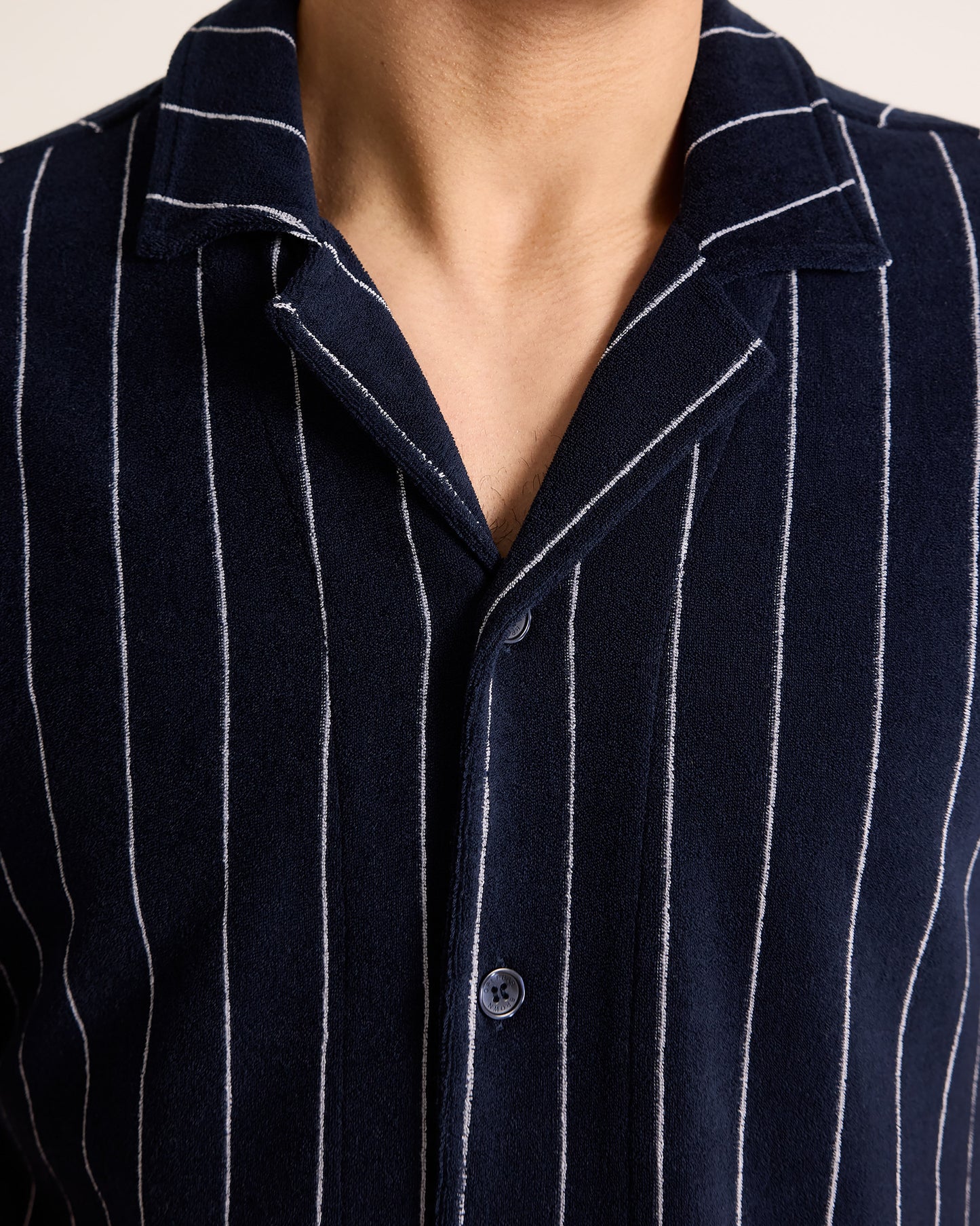 Navy pinstripe shirt with collar and buttons on a neutral background