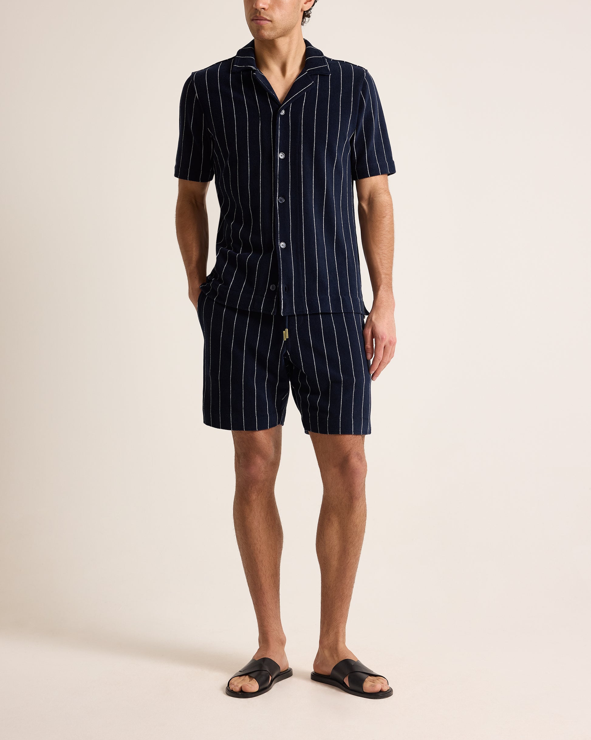 Person wearing a navy pinstripe pajama set on a beige background