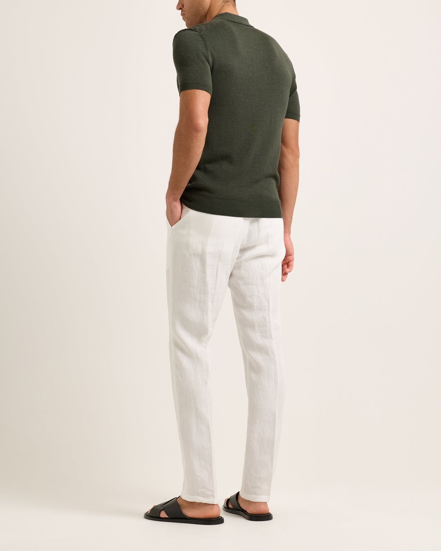 Model wearing a green polo shirt and white pants on a plain background