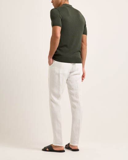 Model wearing a green polo shirt and white pants on a plain background