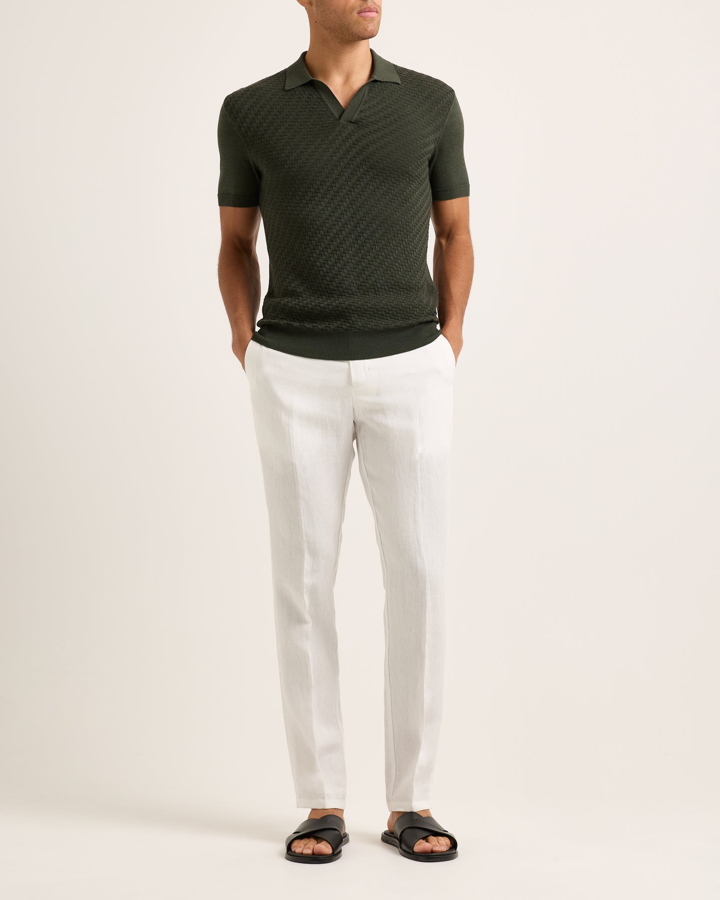 Model wearing a green polo shirt and white pants on a plain background