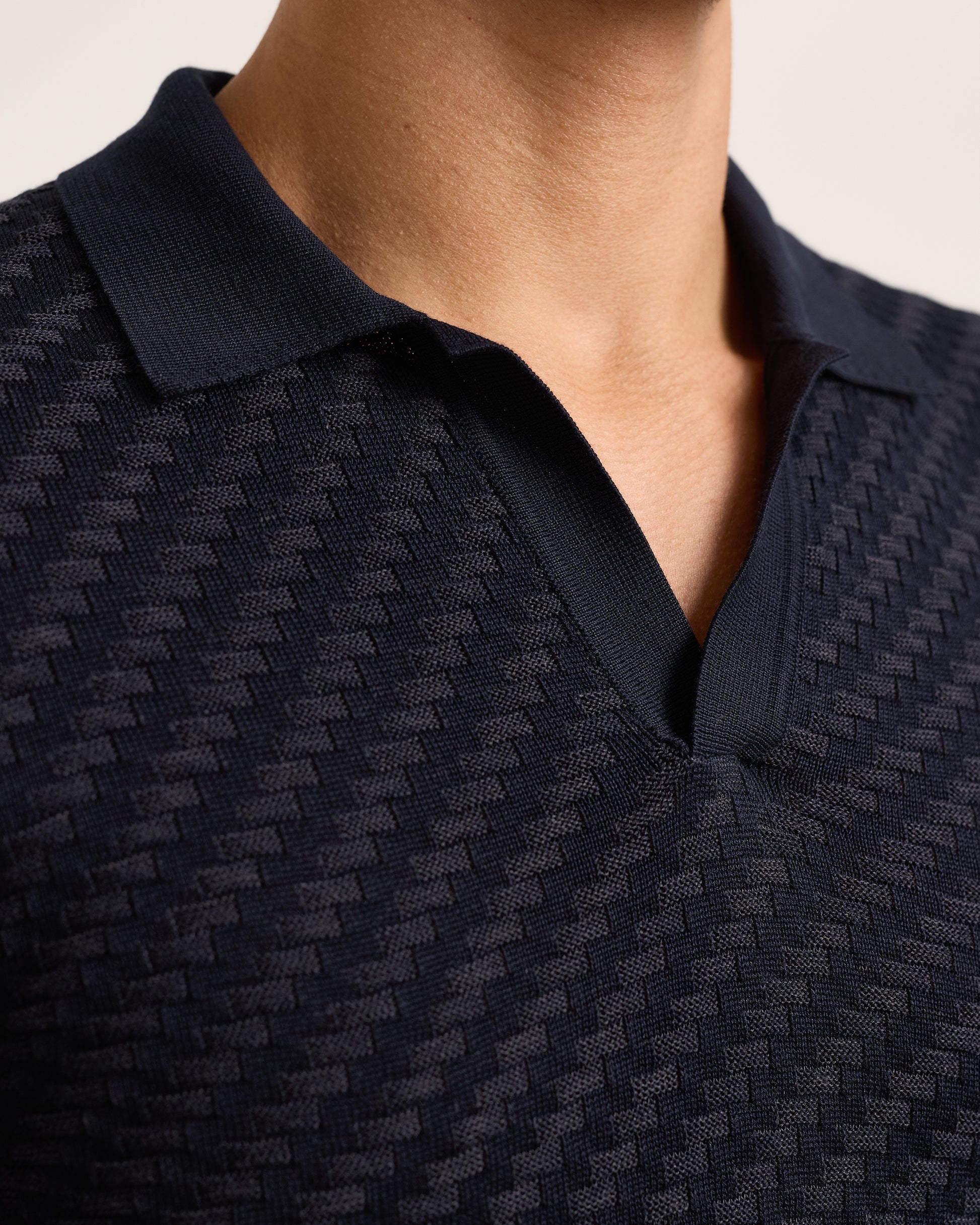 Close-up of navy textured polo shirt on a plain background