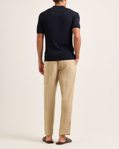 Model wearing navy textured polo shirt with beige trousers on a plain background