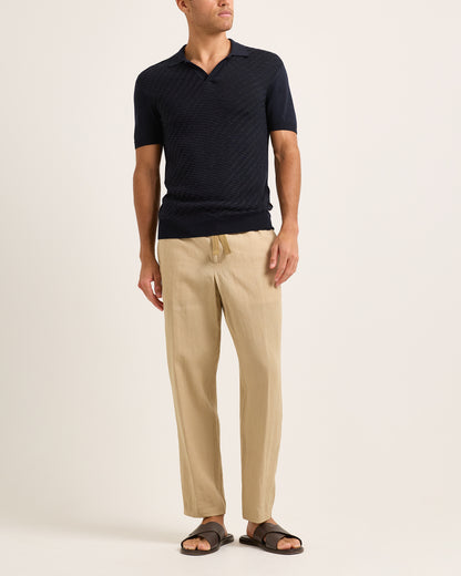 Model wearing navy textured polo shirt with beige trousers on a plain background