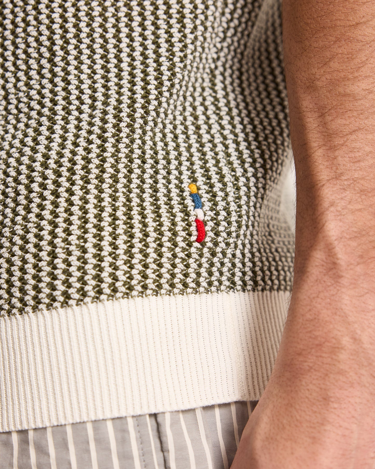 Close-up of a textured fabric with a small embroidered design on a person's arm.