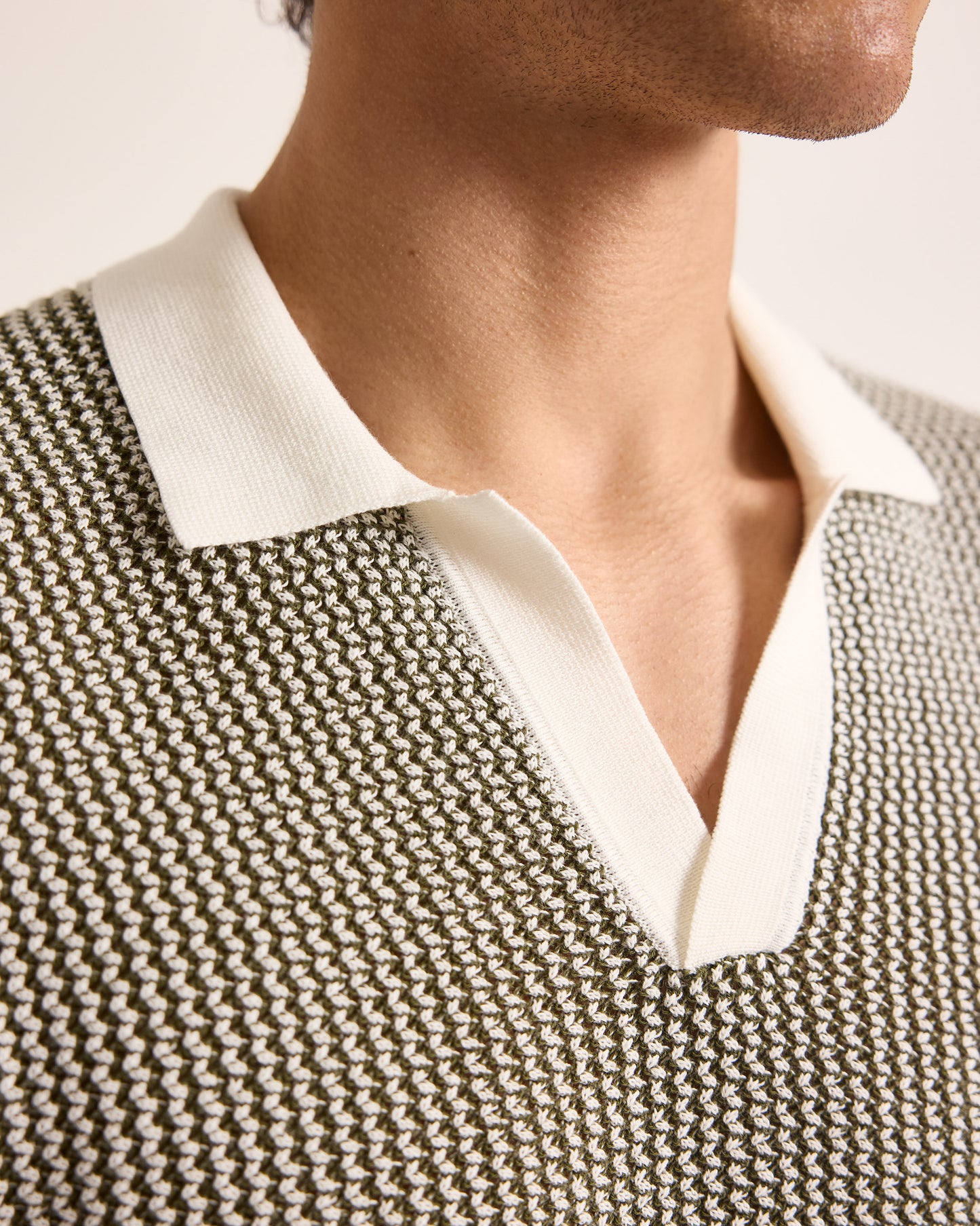 Close-up of a person wearing a textured sweater over a white shirt.