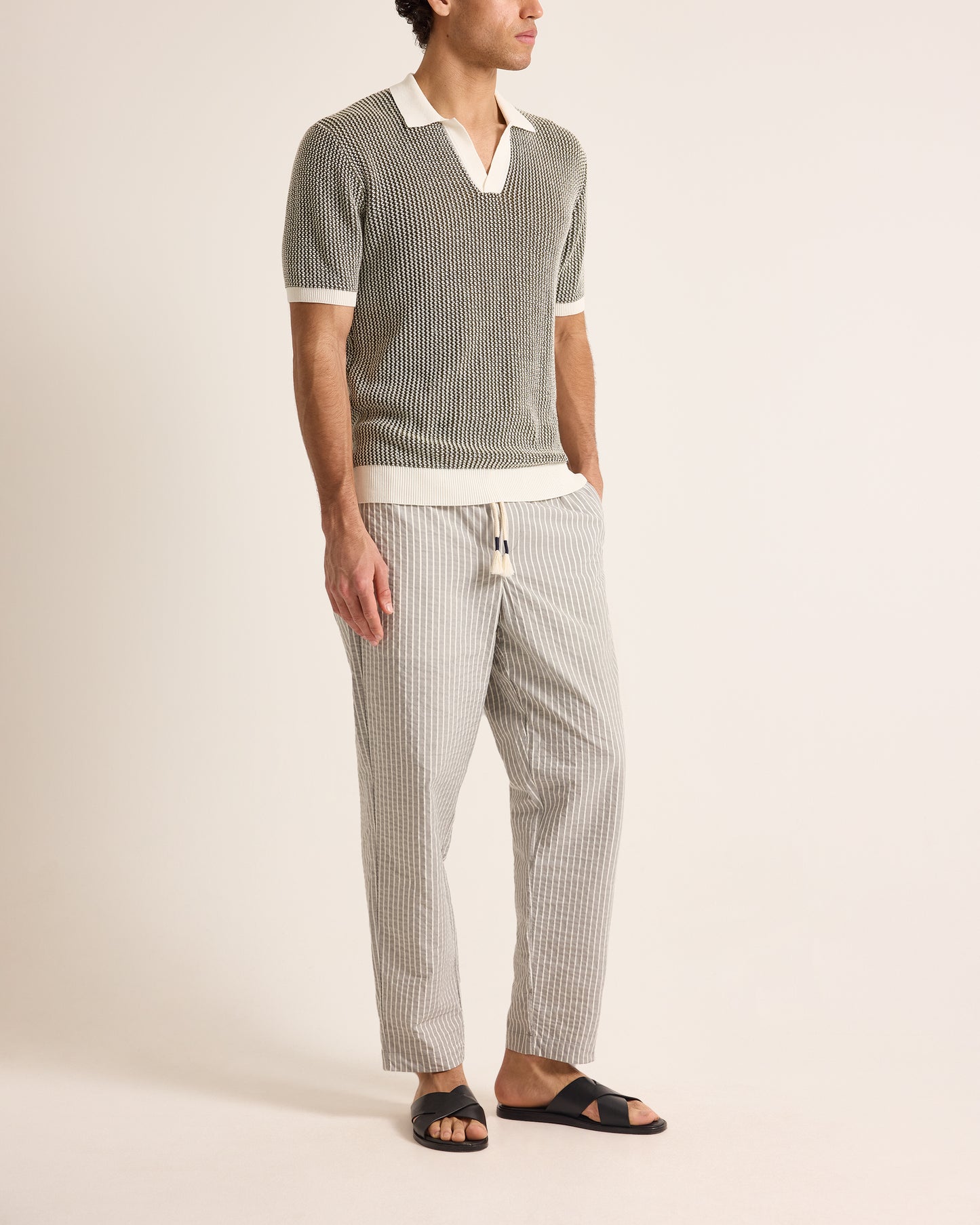 Man wearing a striped shirt and pants on a plain background