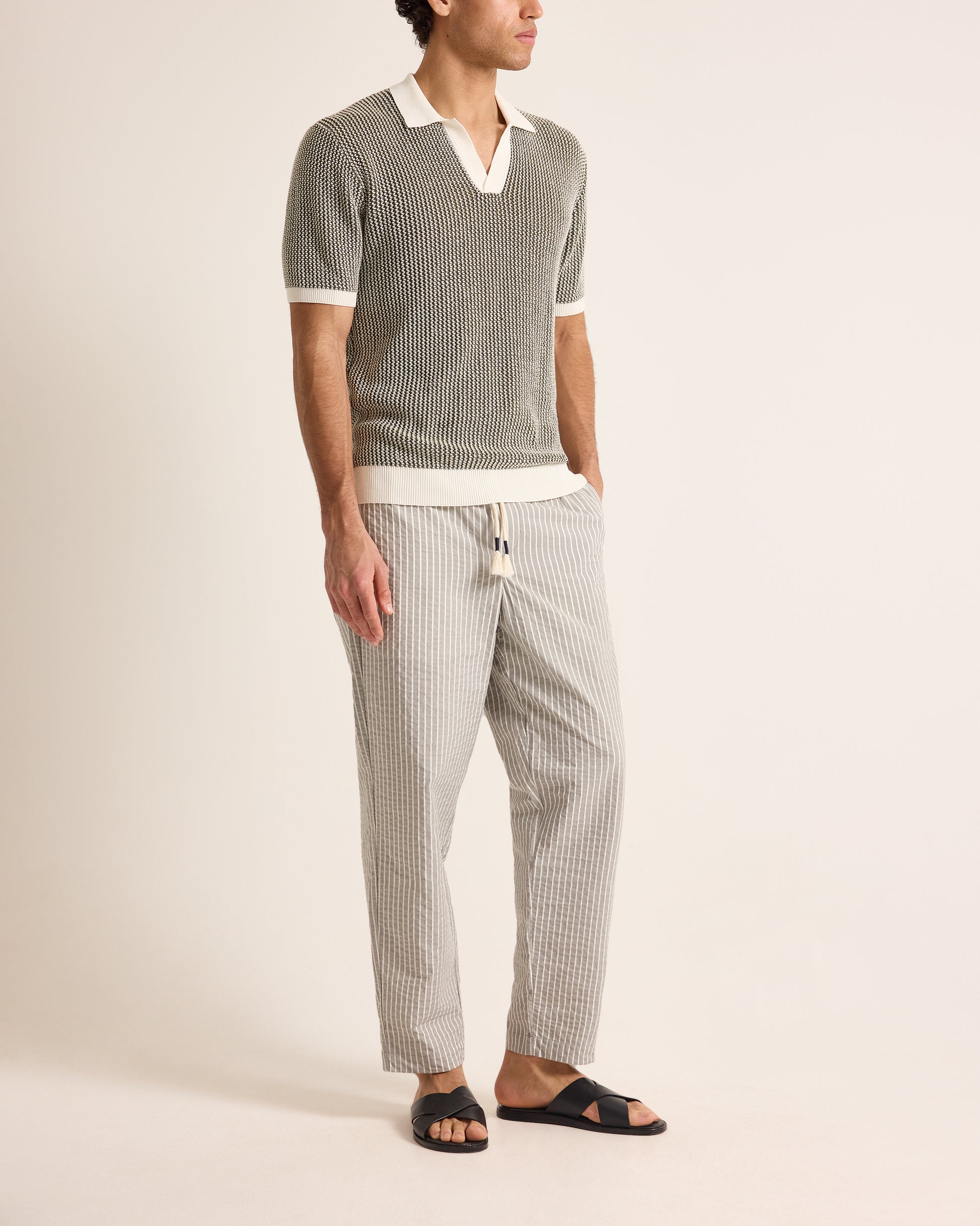 Man wearing a striped shirt and pants on a plain background