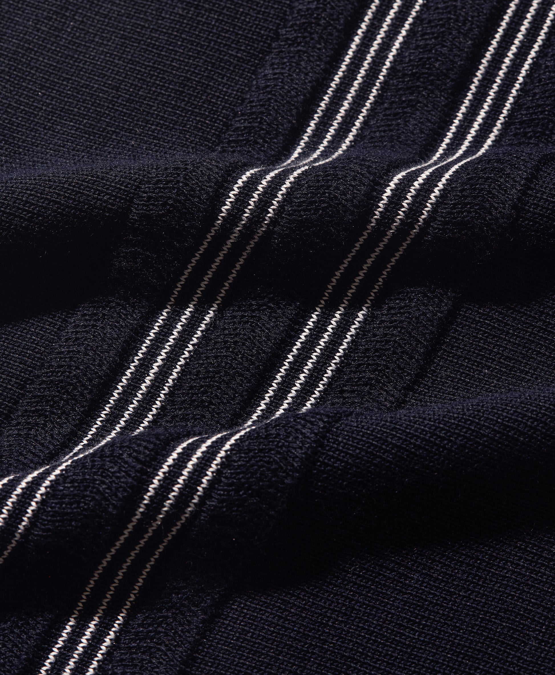 Close-up of a dark navy knit fabric with diagonal metallic silver stripes.