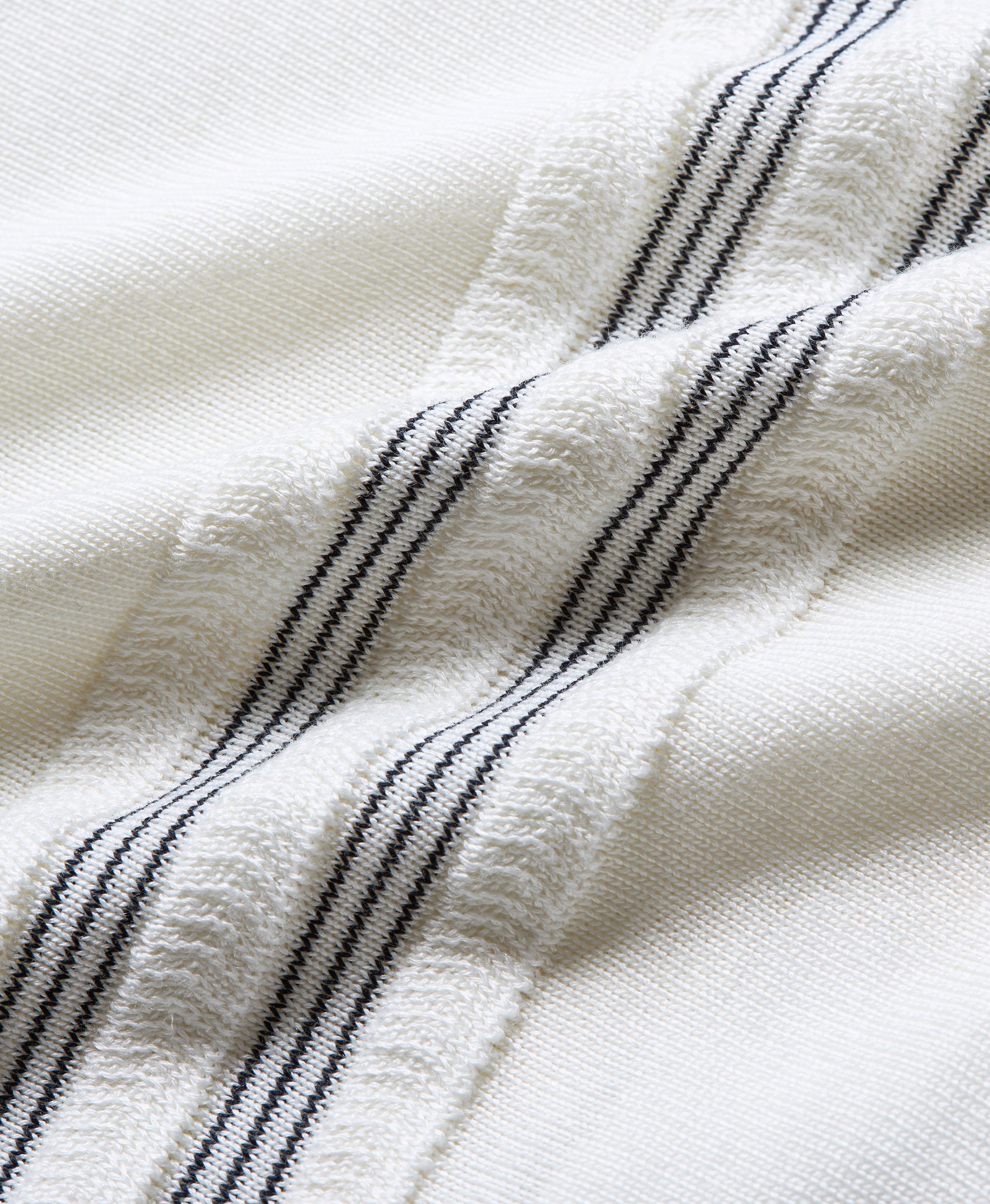 Close-up of a textured off-white fabric with three vertical black stripes.