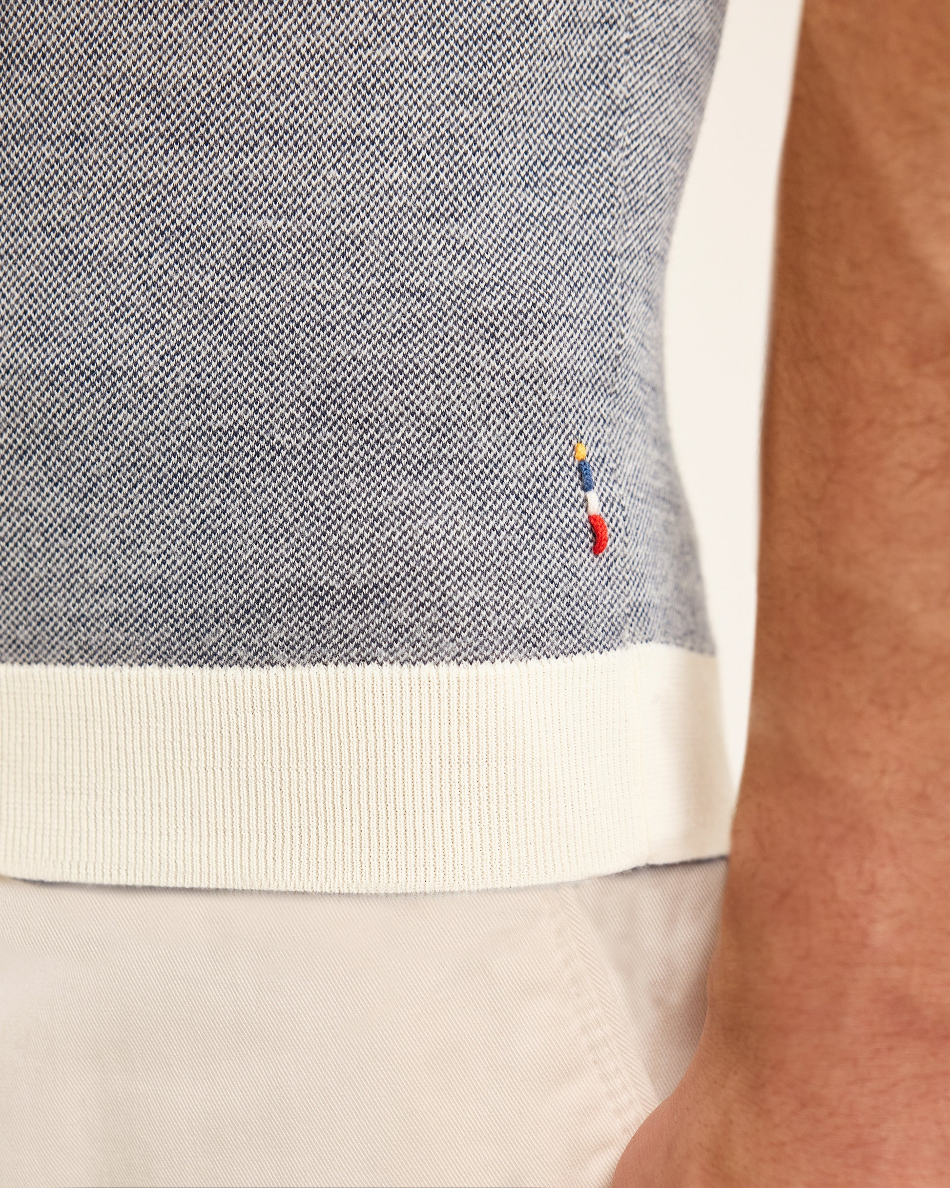 Close-up of a person wearing a grey polo with a brand logo