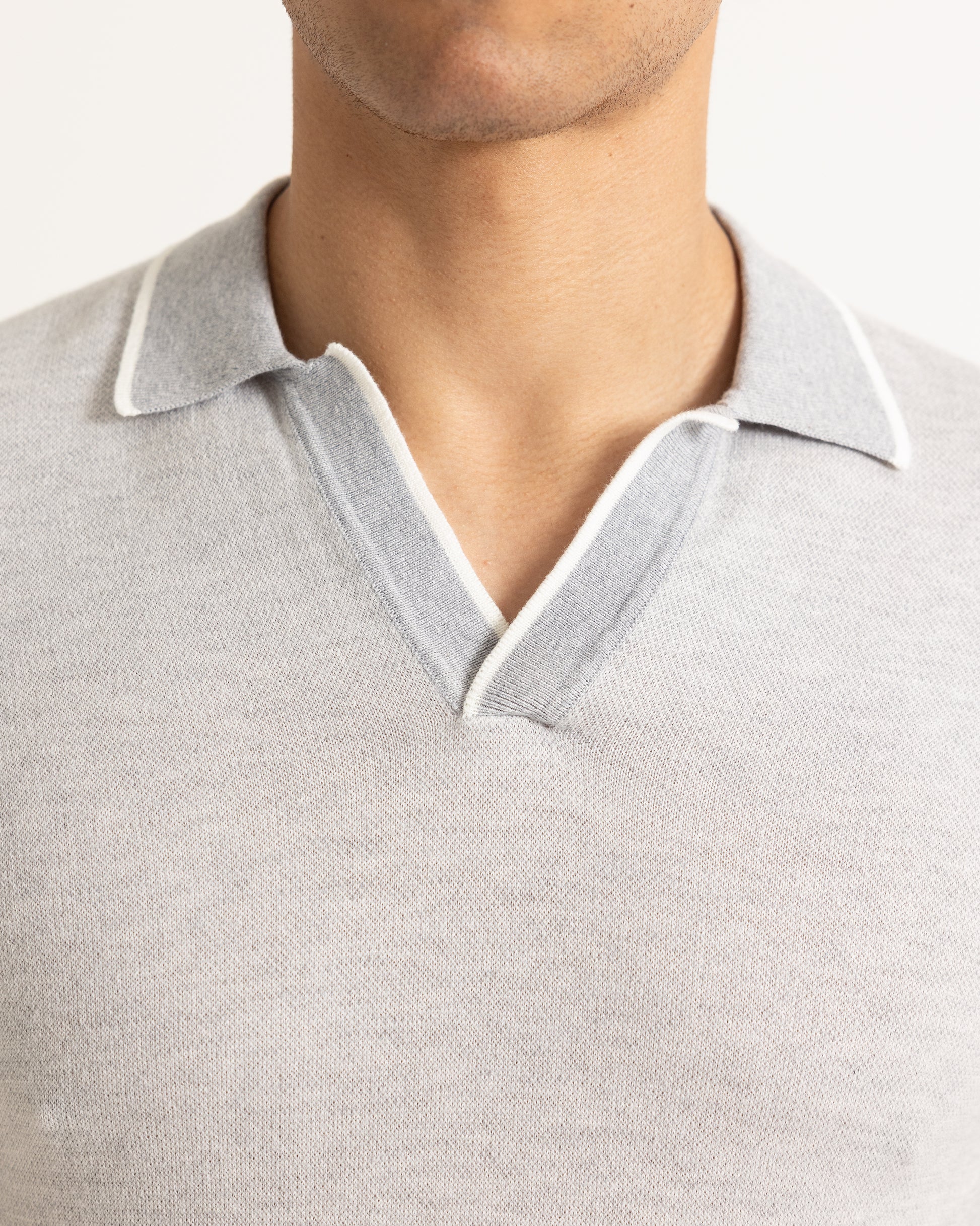 Close-up of a gray polo shirt with white trim on a neutral background