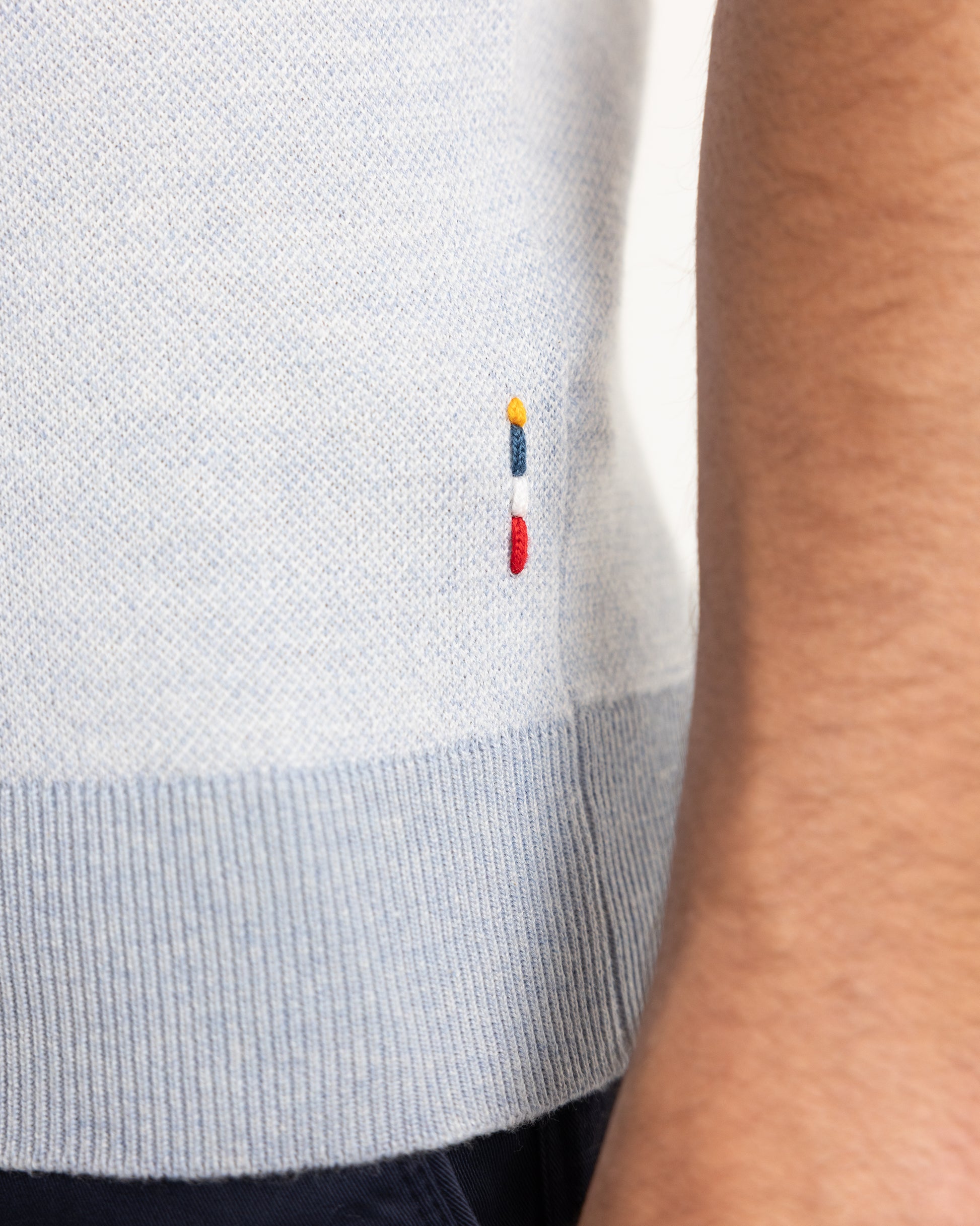 Closeup of blue knitted polo shirt with branded embroidery