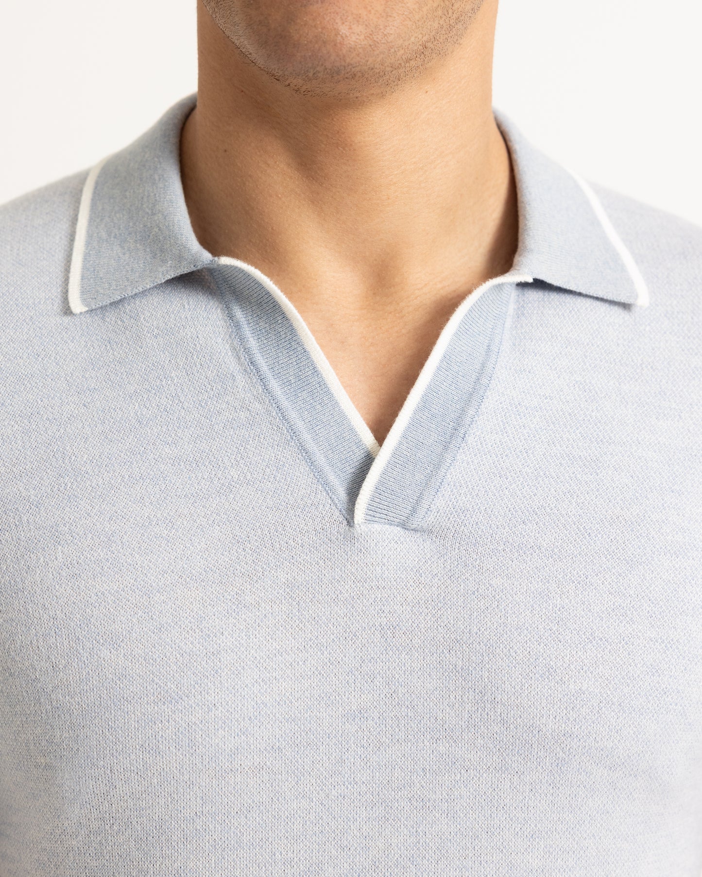 Close-up of a light gray polo shirt with white trim on a neutral background