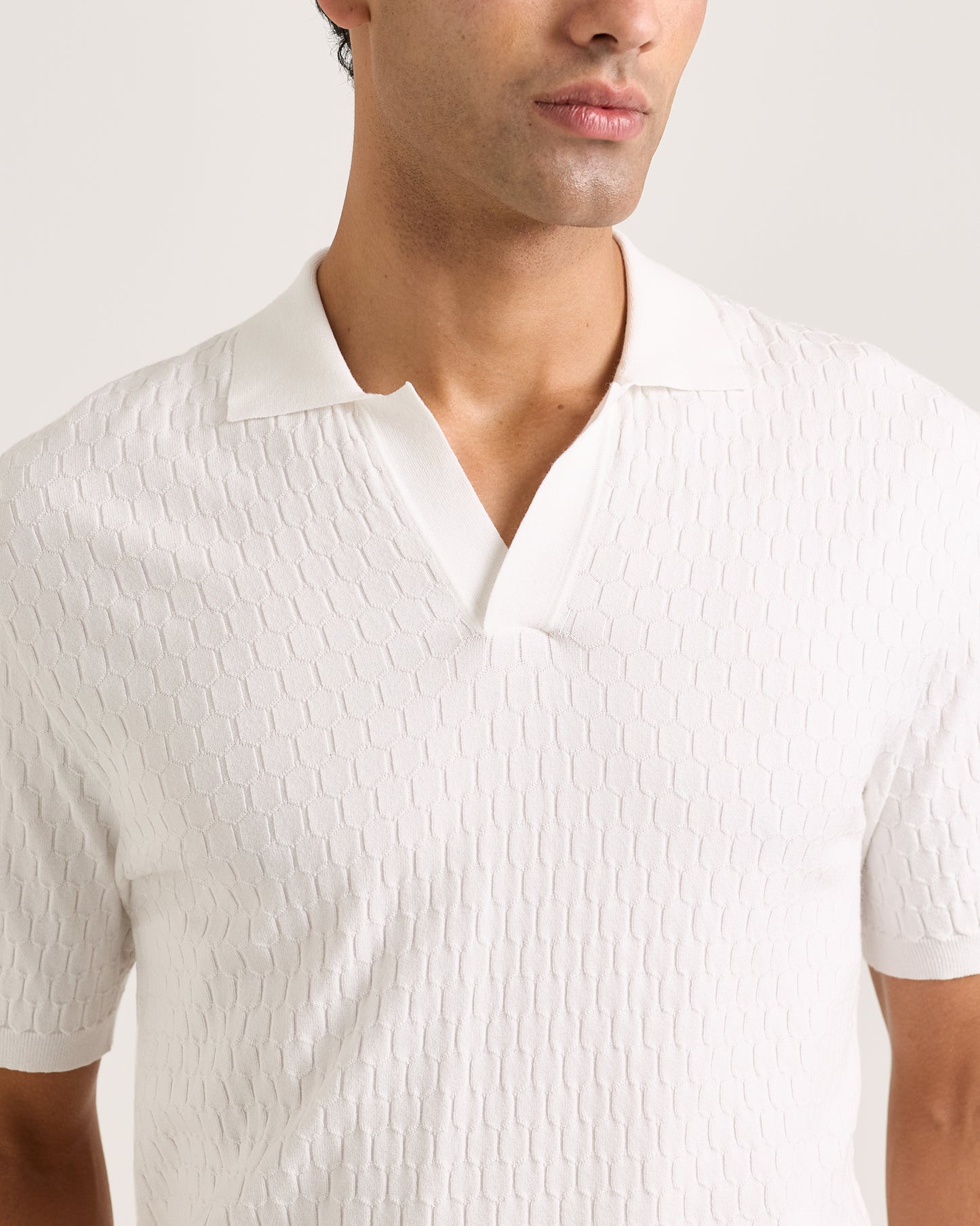 Close-up of a man wearing a textured white shirt against a plain background