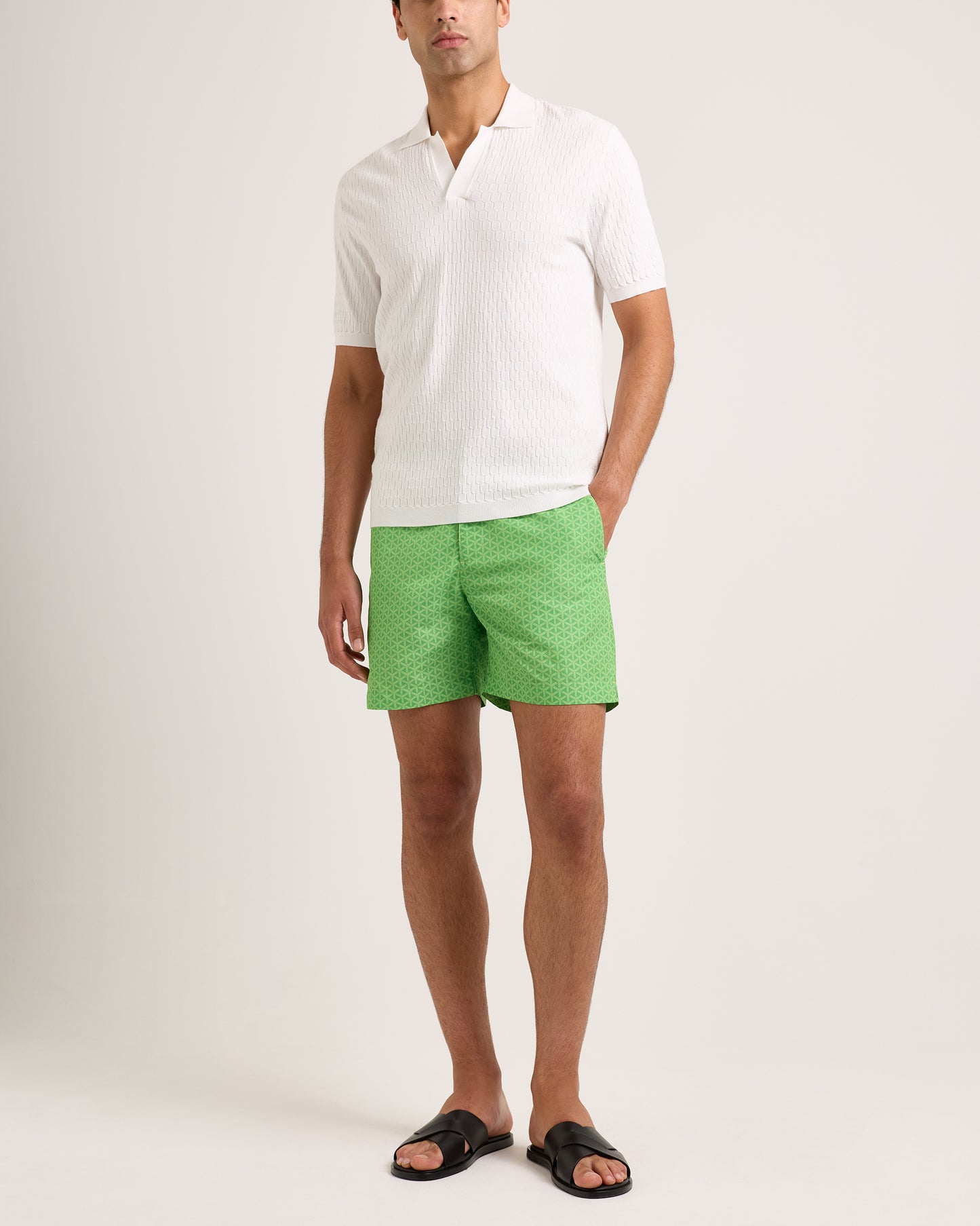 Man wearing a white shirt and green shorts on a plain background