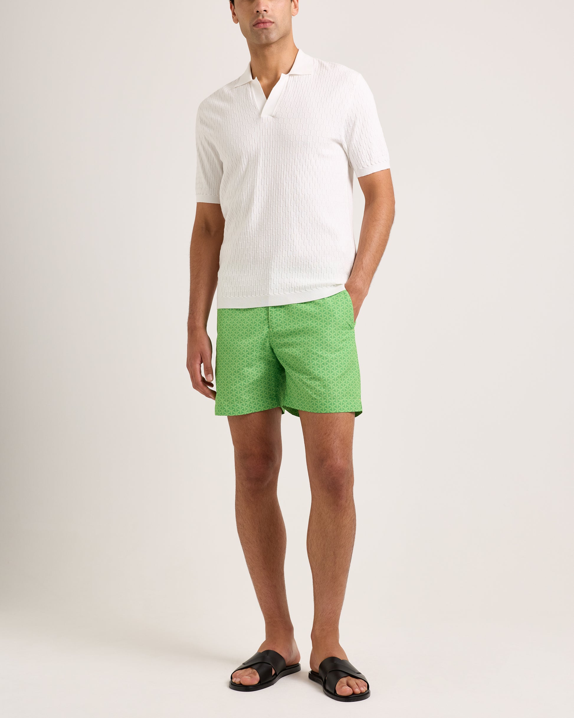 Man wearing a white shirt and green shorts on a plain background