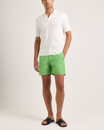 Man wearing a white shirt and green shorts on a plain background