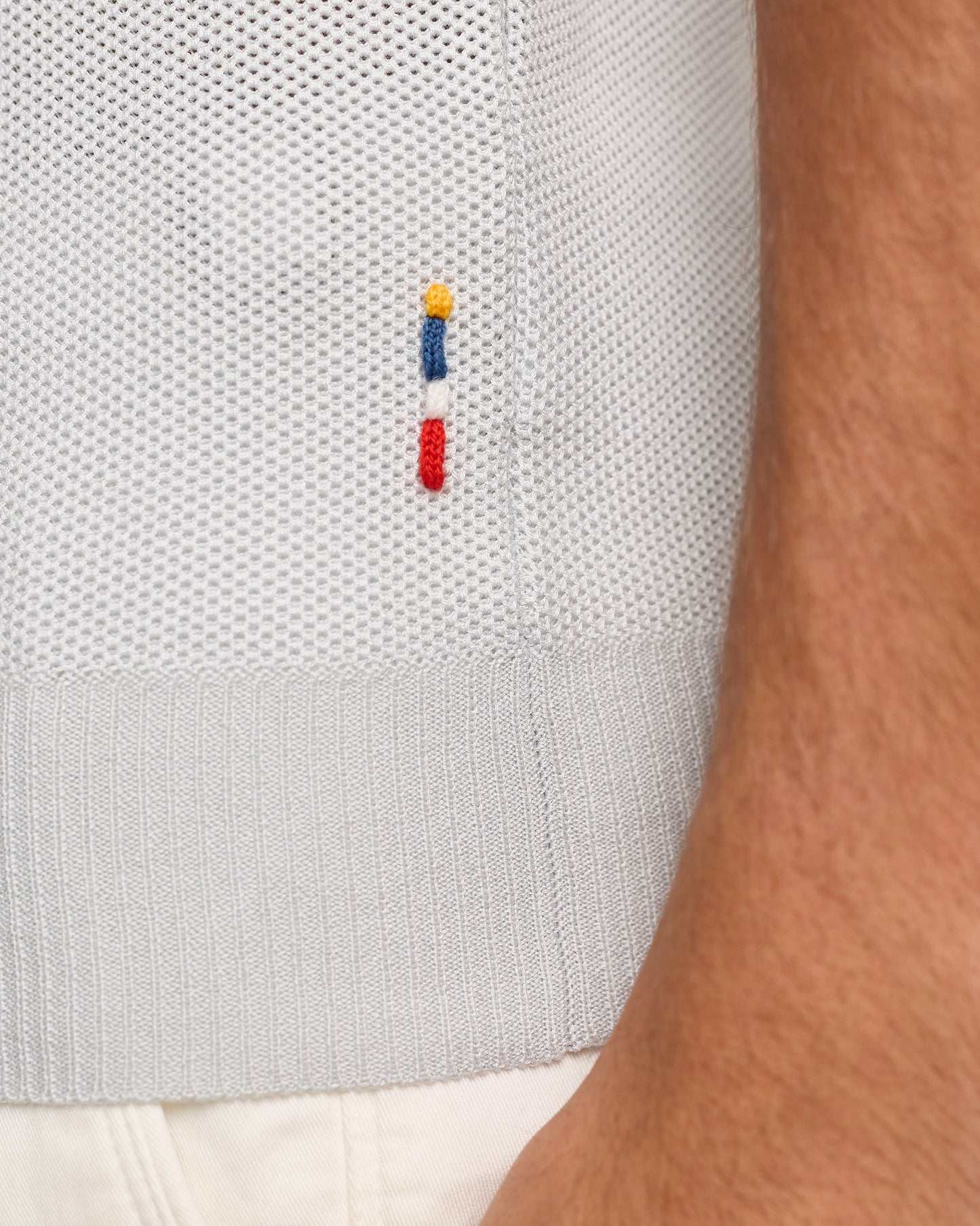 Close-up of  textured polo with a small embroidered logo on a white background.