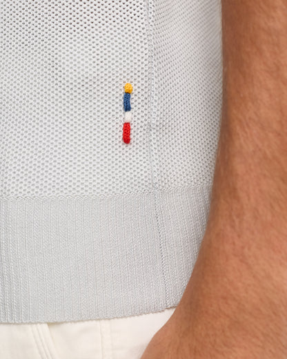 Close-up of  textured polo with a small embroidered logo on a white background.