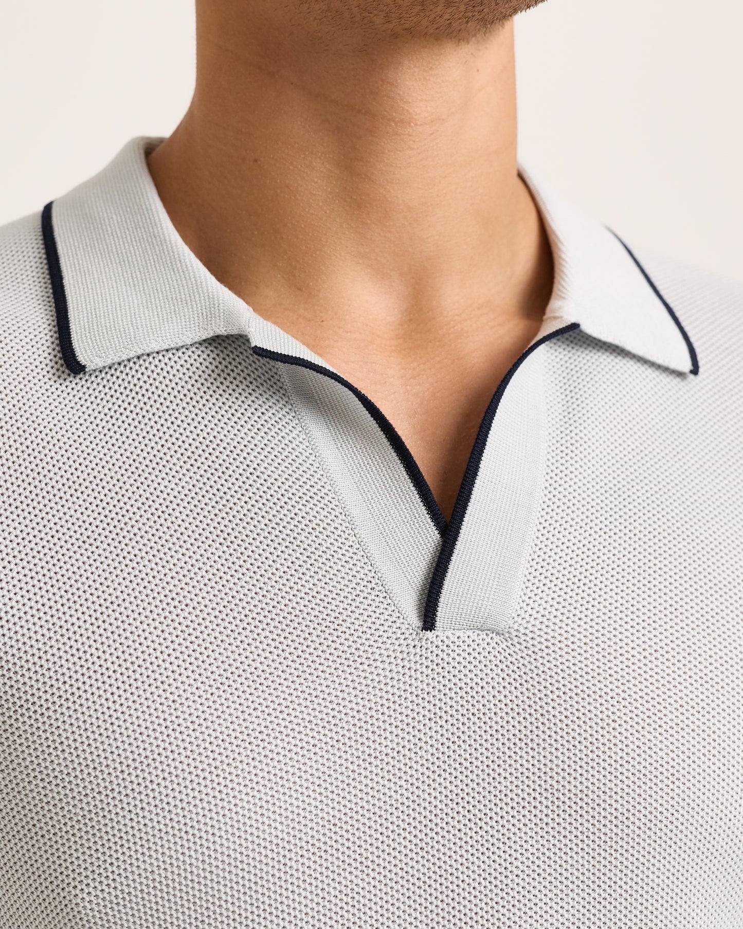 Close-up of light blue polo shirt with black trim on a white background