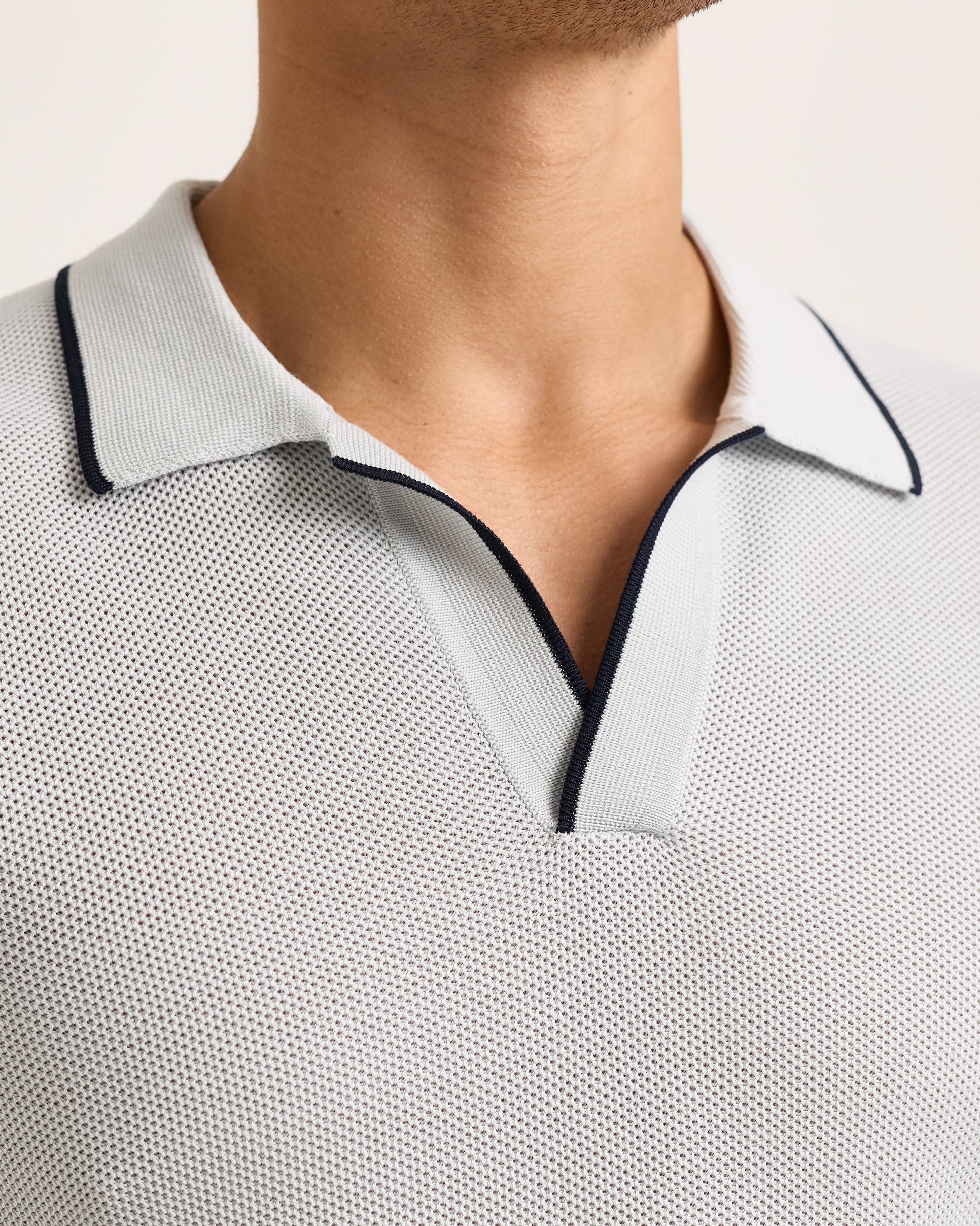 Close-up of light blue polo shirt with black trim on a white background