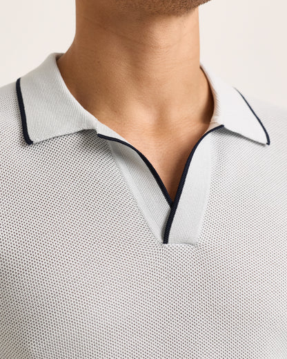 Close-up of light blue polo shirt with black trim on a white background