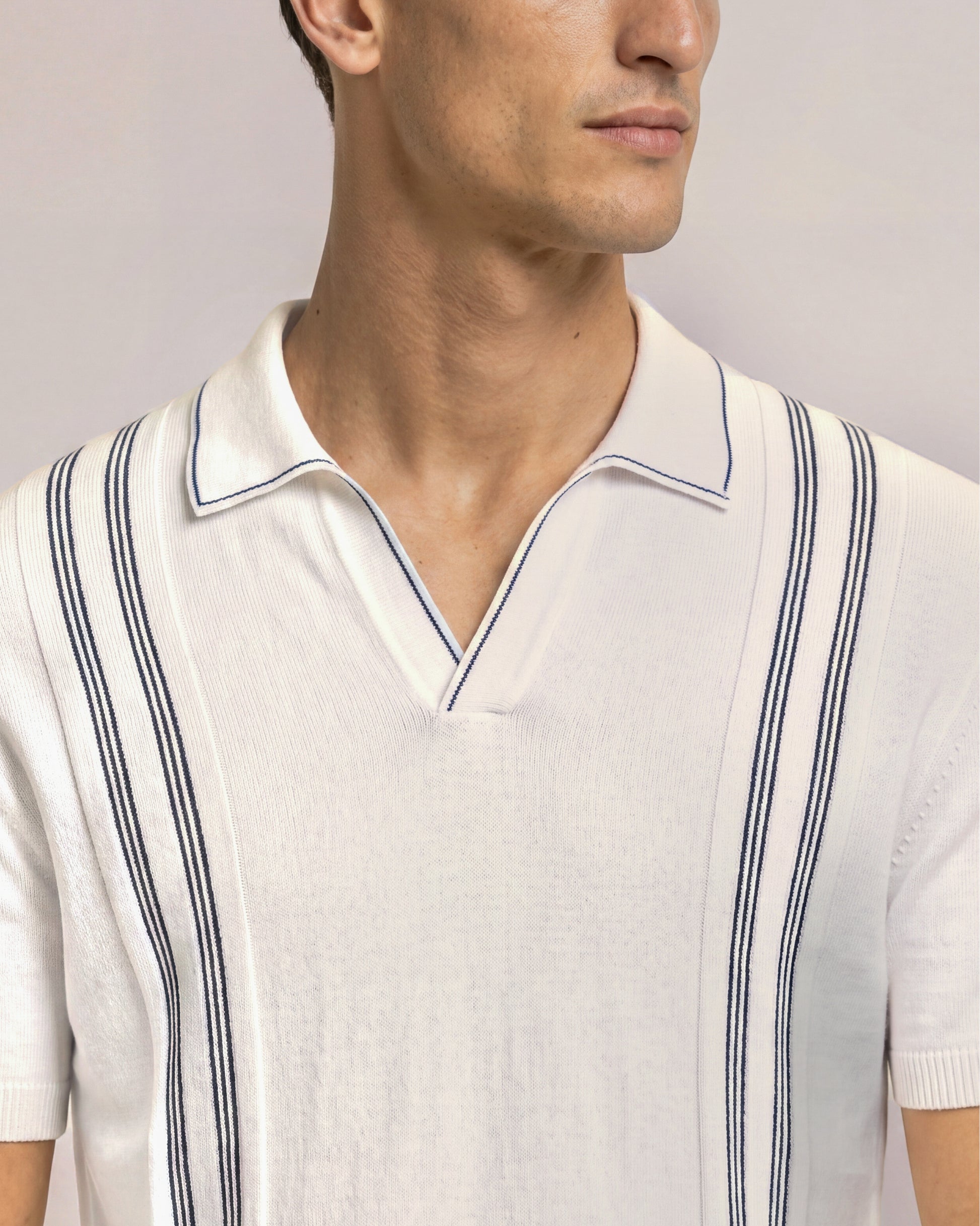 Close-up of a man wearing a white polo shirt with blue trim on a plain background