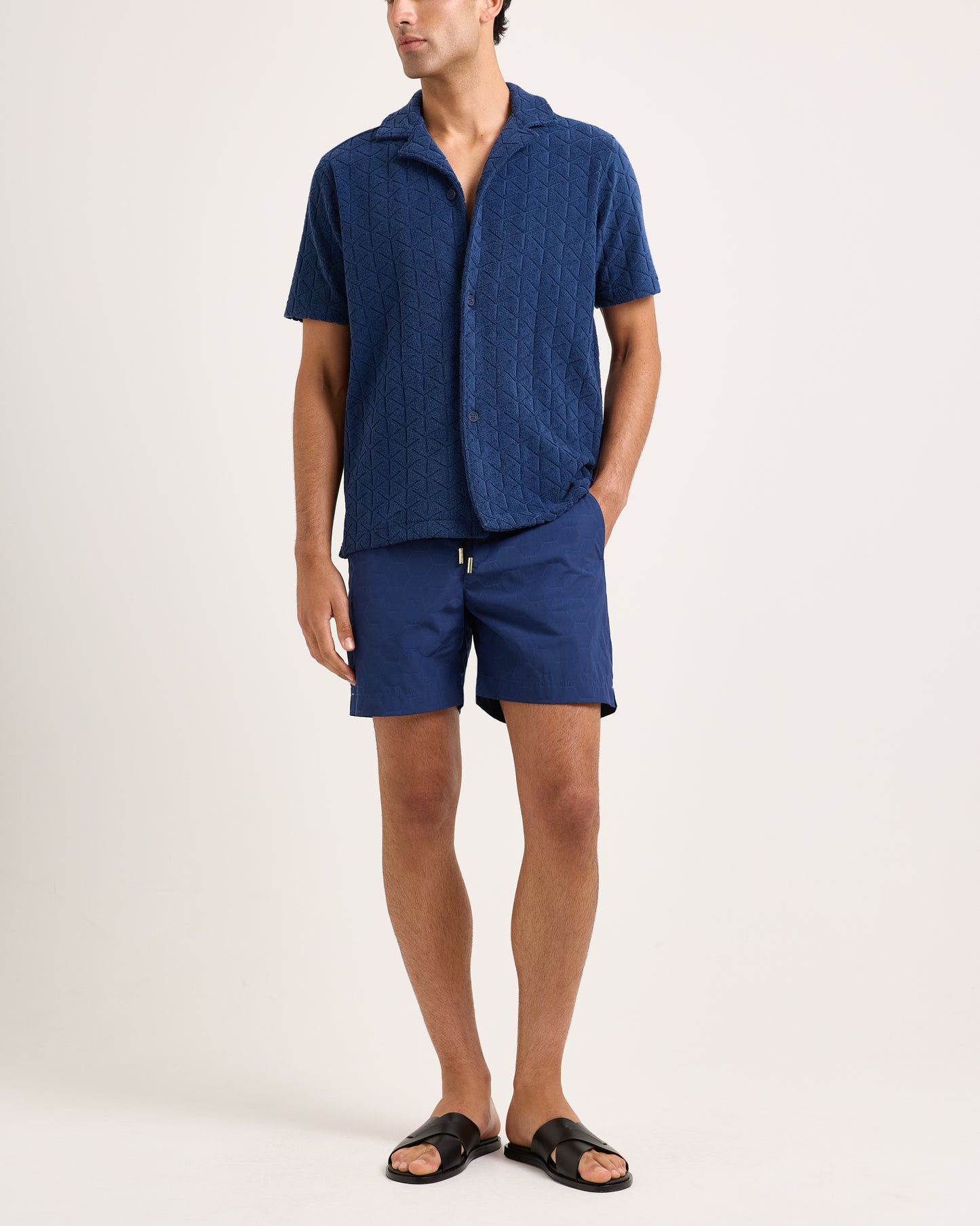 Man wearing a blue textured shirt and shorts set on a white background