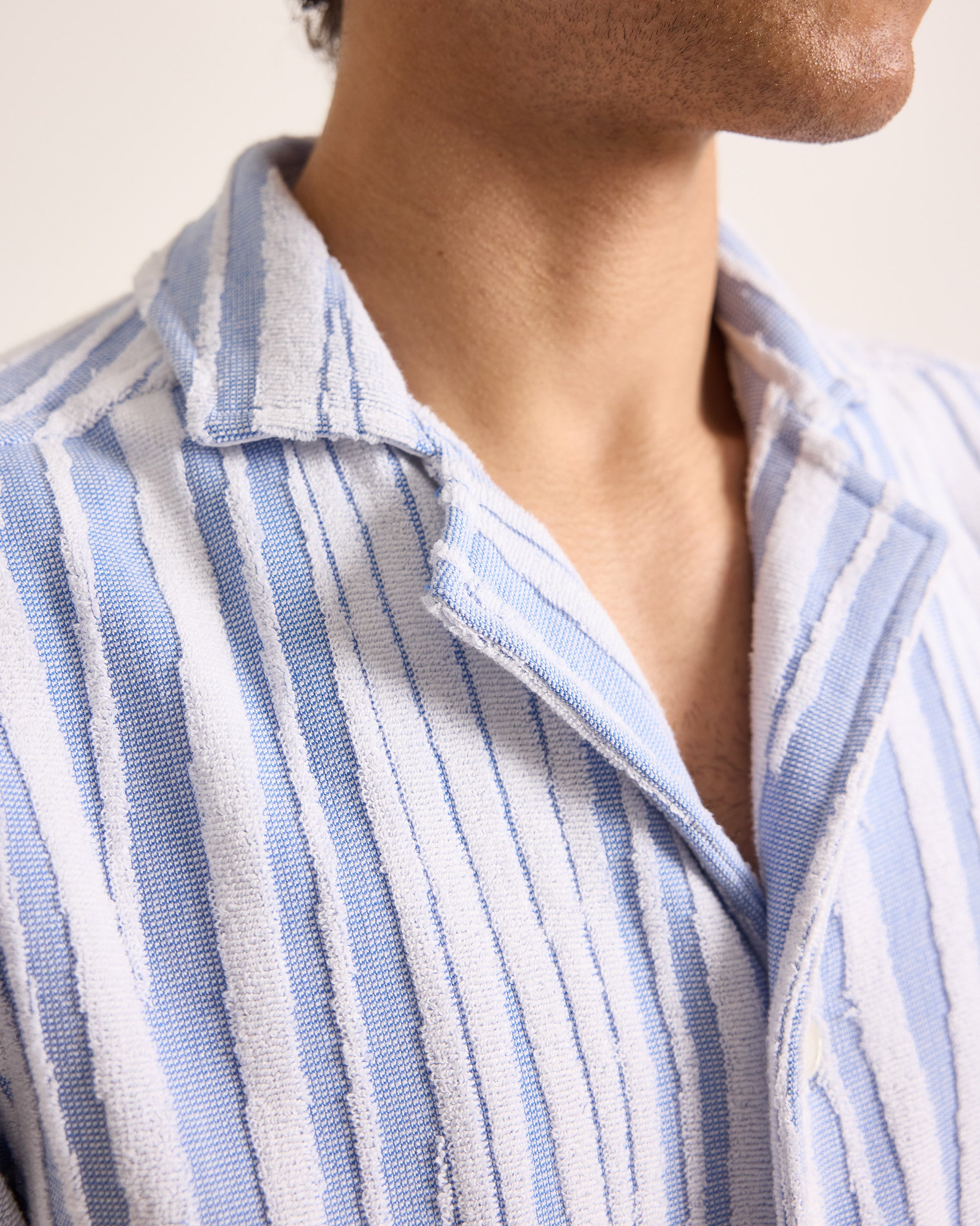 Close-up of a person wearing a blue and white striped shirt.
