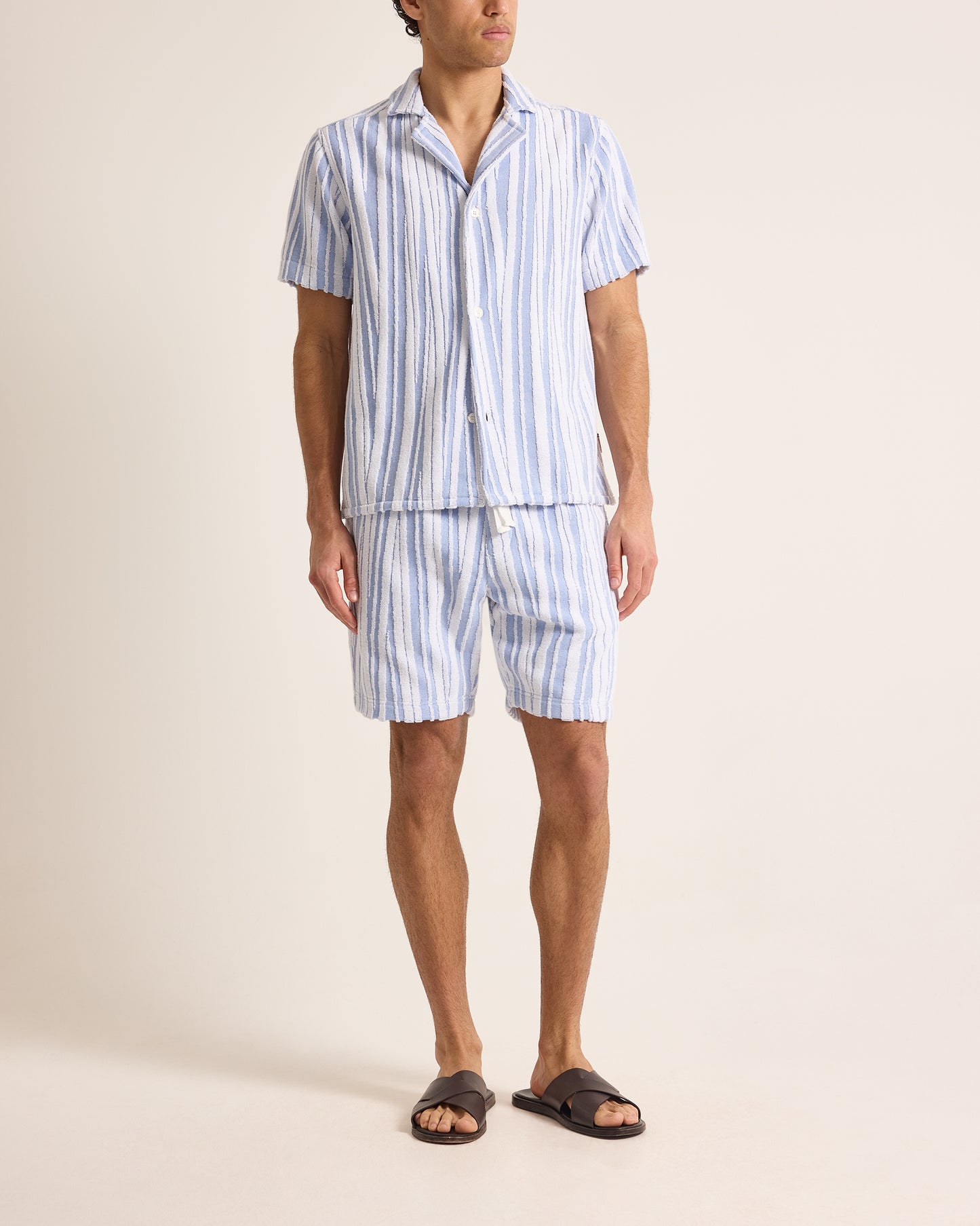Person wearing a blue and white striped pajama set on a beige background